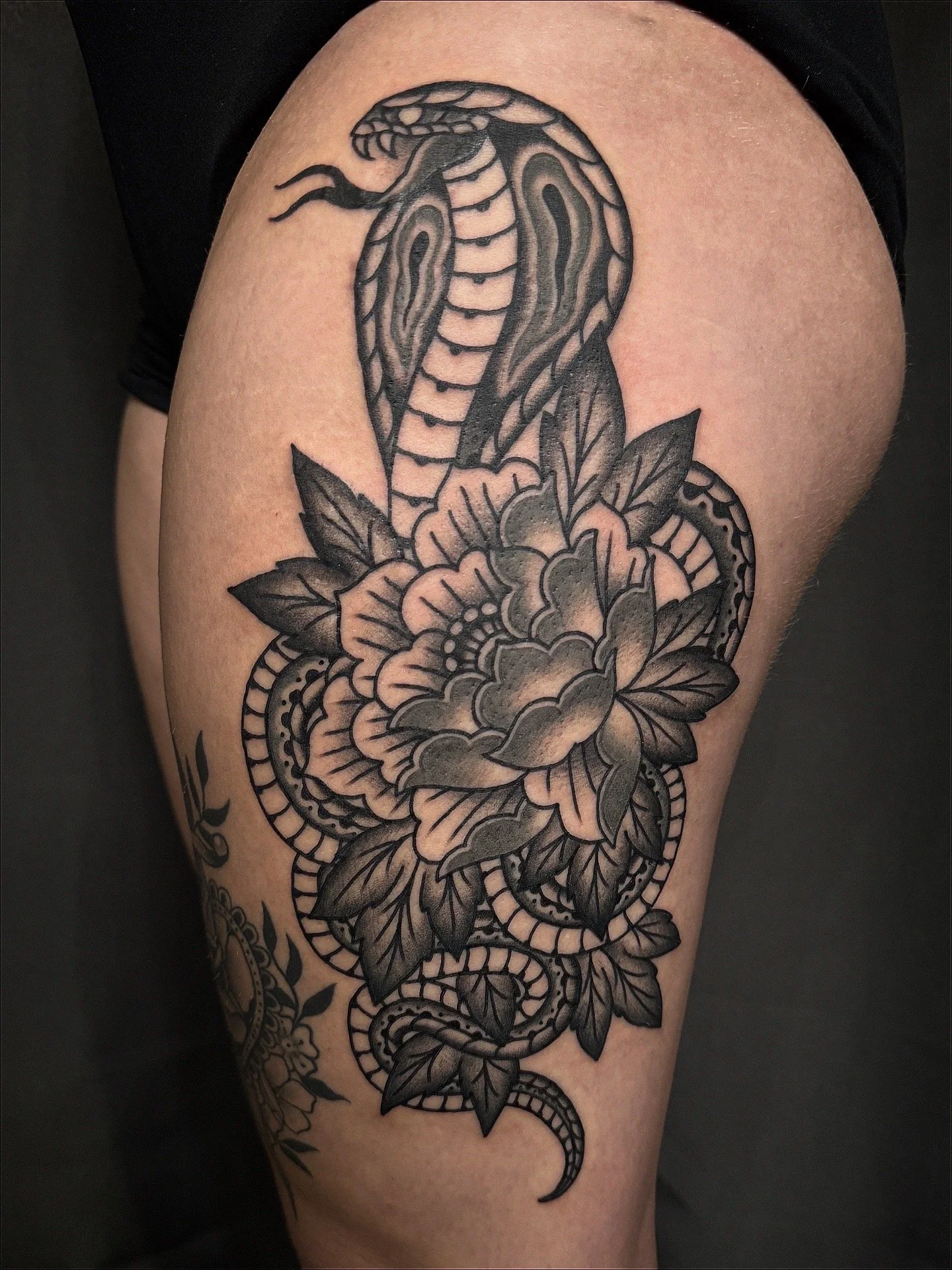 Tattoo of a snake wrapped around a large flower with leaves.