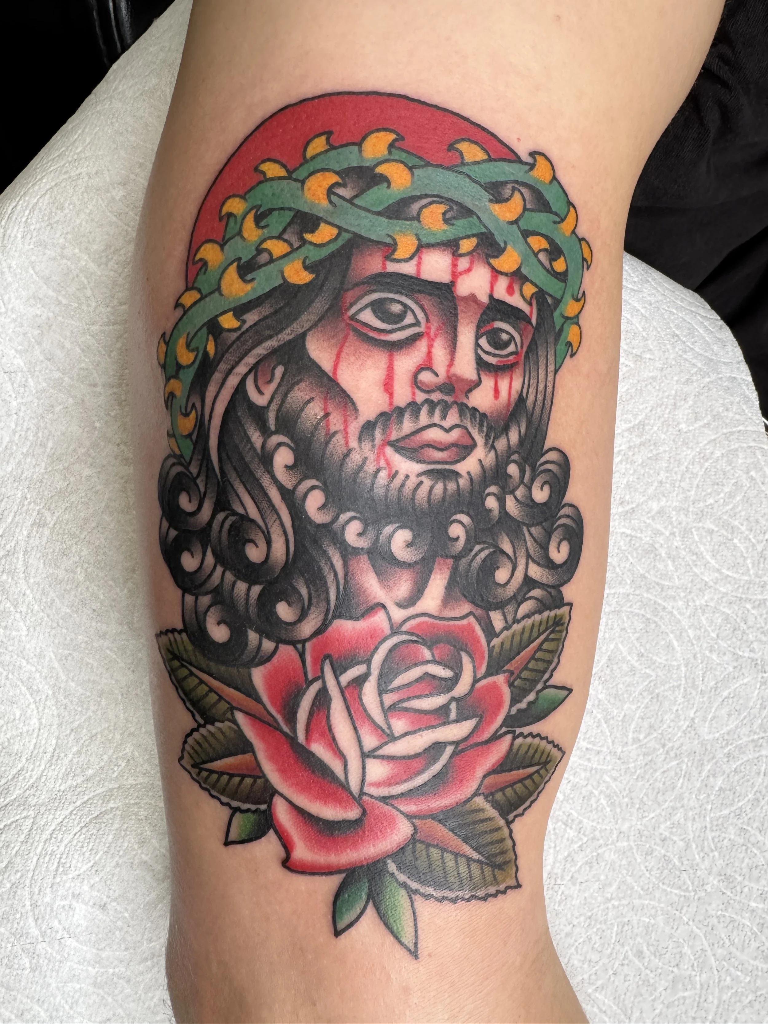 Tattoo of Jesus Christ with crown of thorns, blood tears, and a rose below.