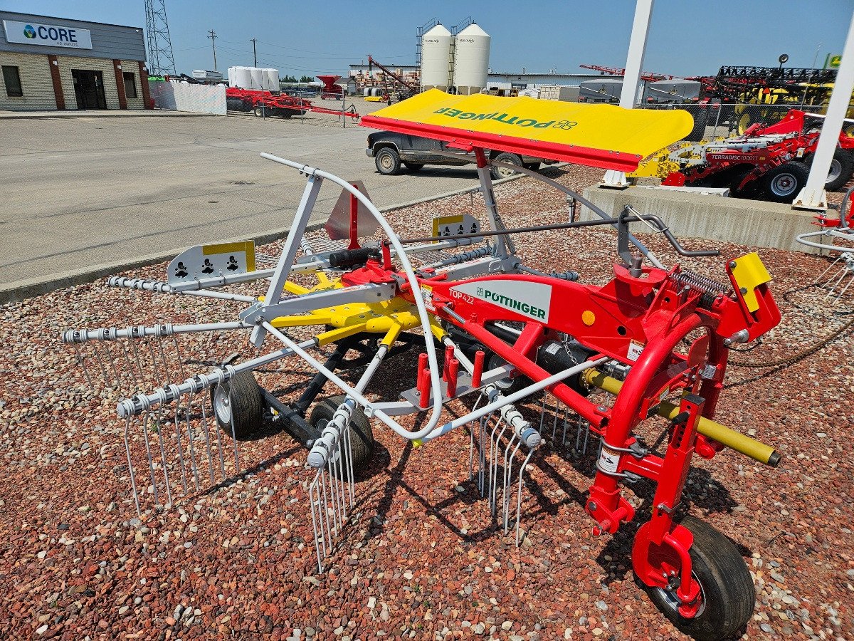 A red and yellow Pottinger single rotor rake sitting on shale in the R.A. West International yard.