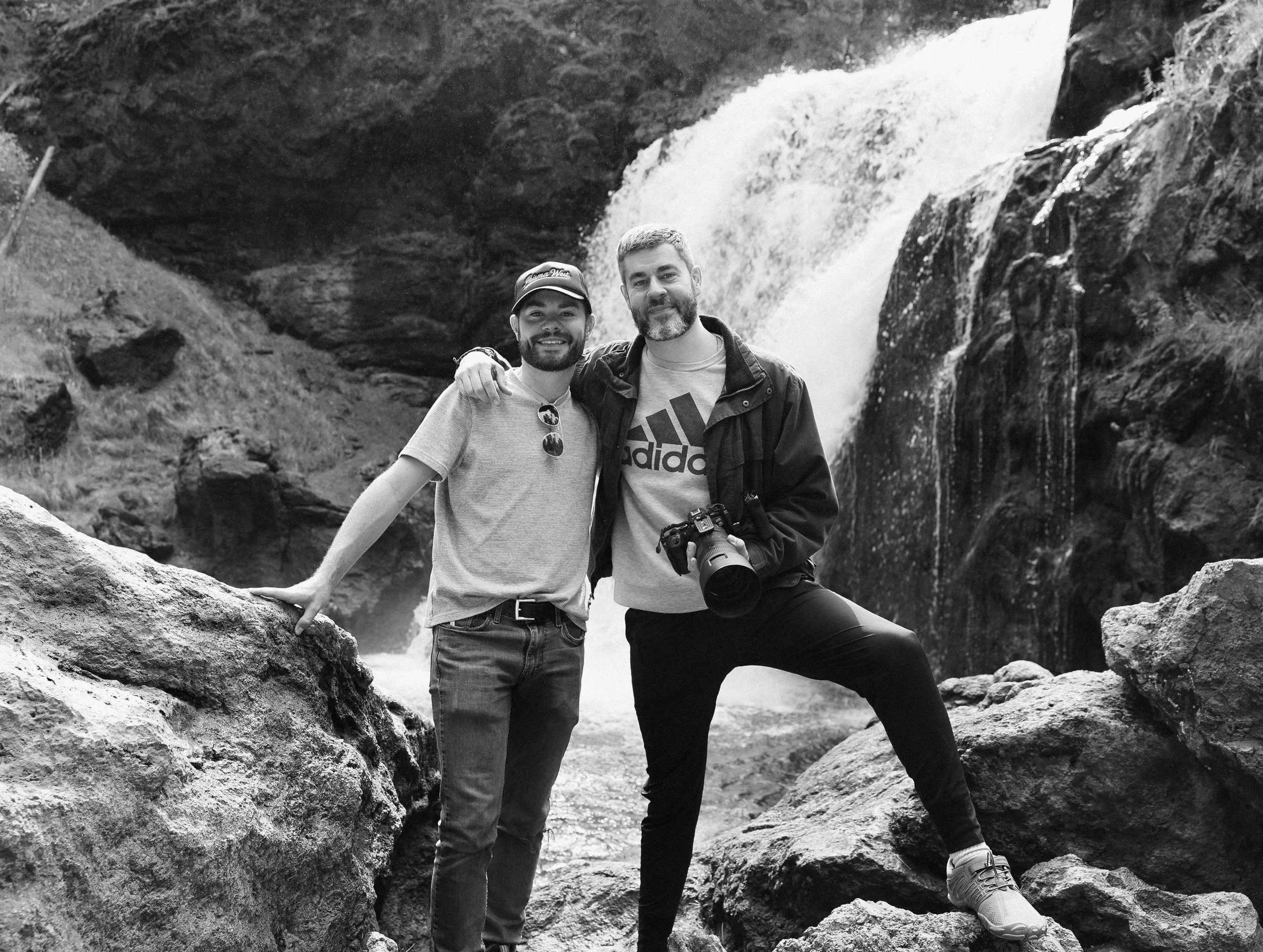 Ryan and Kevin of Prisma West, standing in front of a waterfall in Yellowstone National Park.