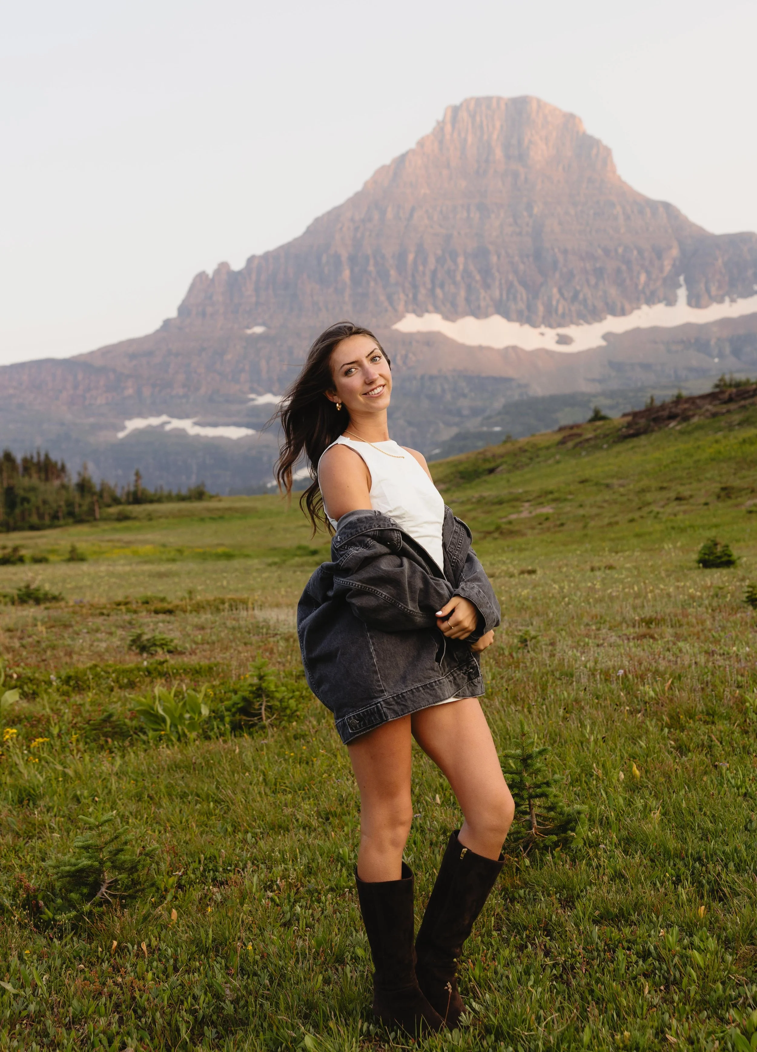 A girl standing in a meadow with a mountainous backdrop in Glacier National Park