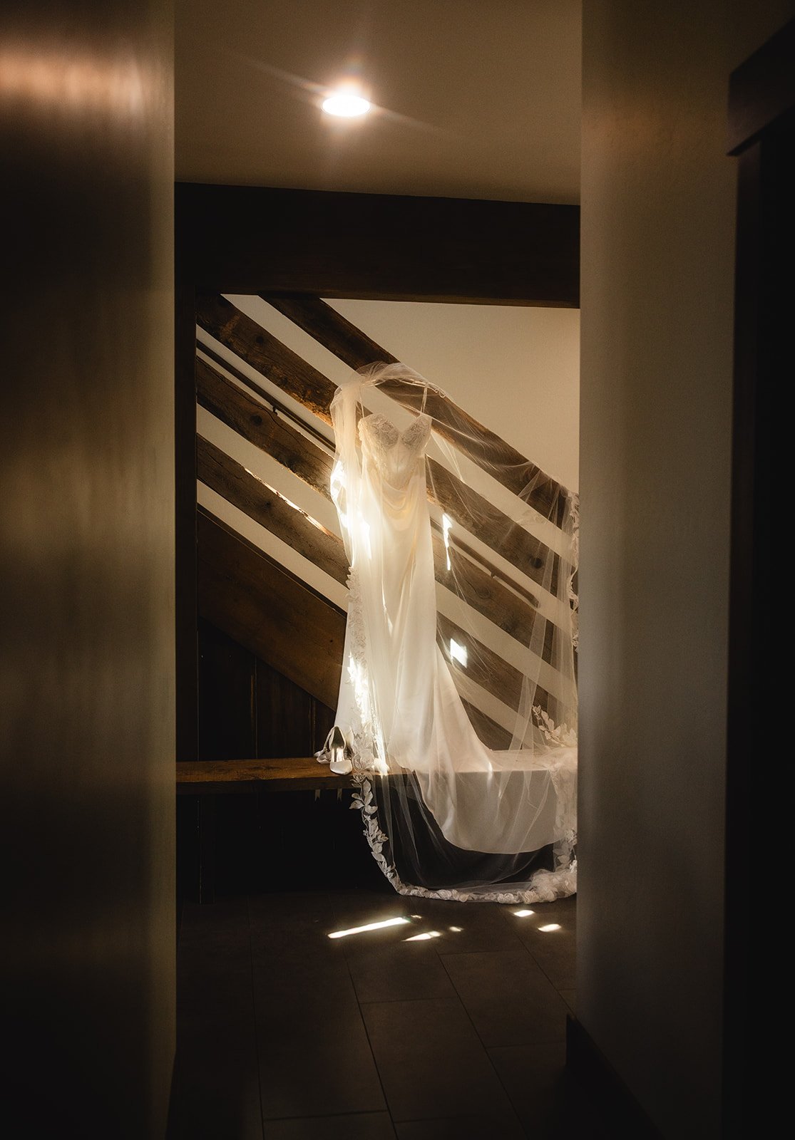 Soft and warm light hitting a wedding dress that hangs on a staircase.