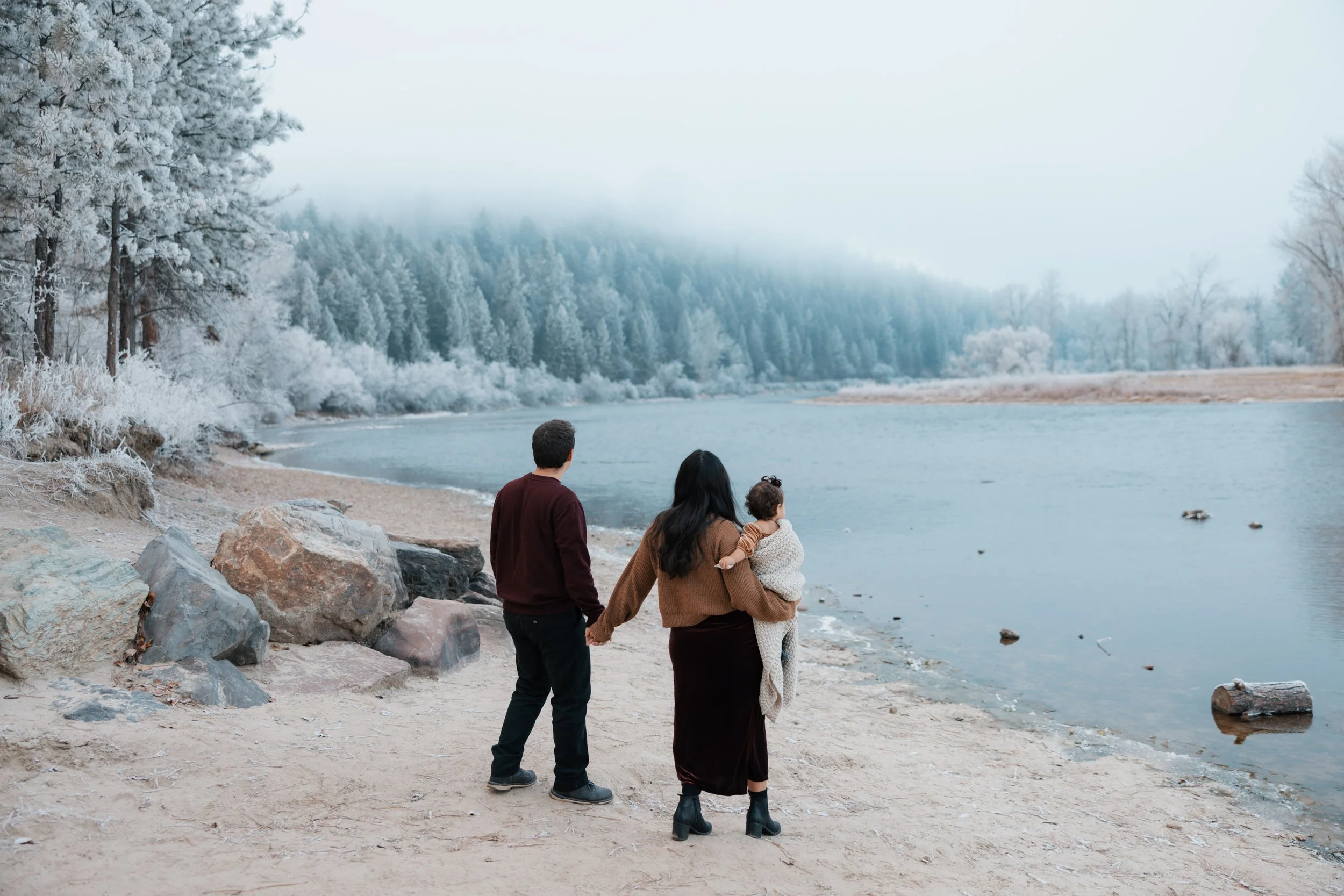 A family in a wintery scene along the river.