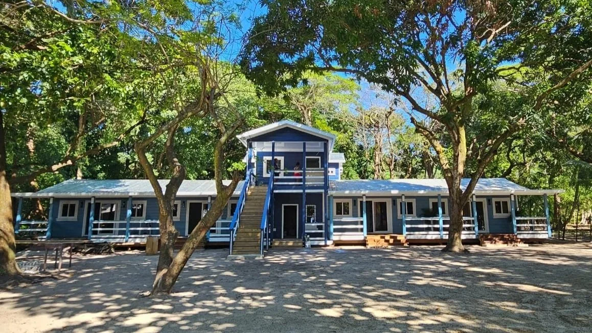 A blue and white building surrounded by trees on a sunny day.