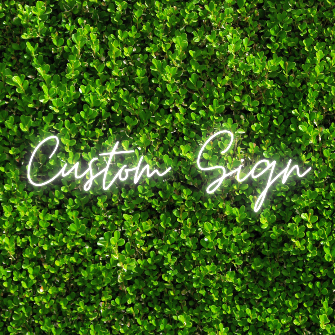 Neon sign reading 'Custom Sign' on a green leafy background.