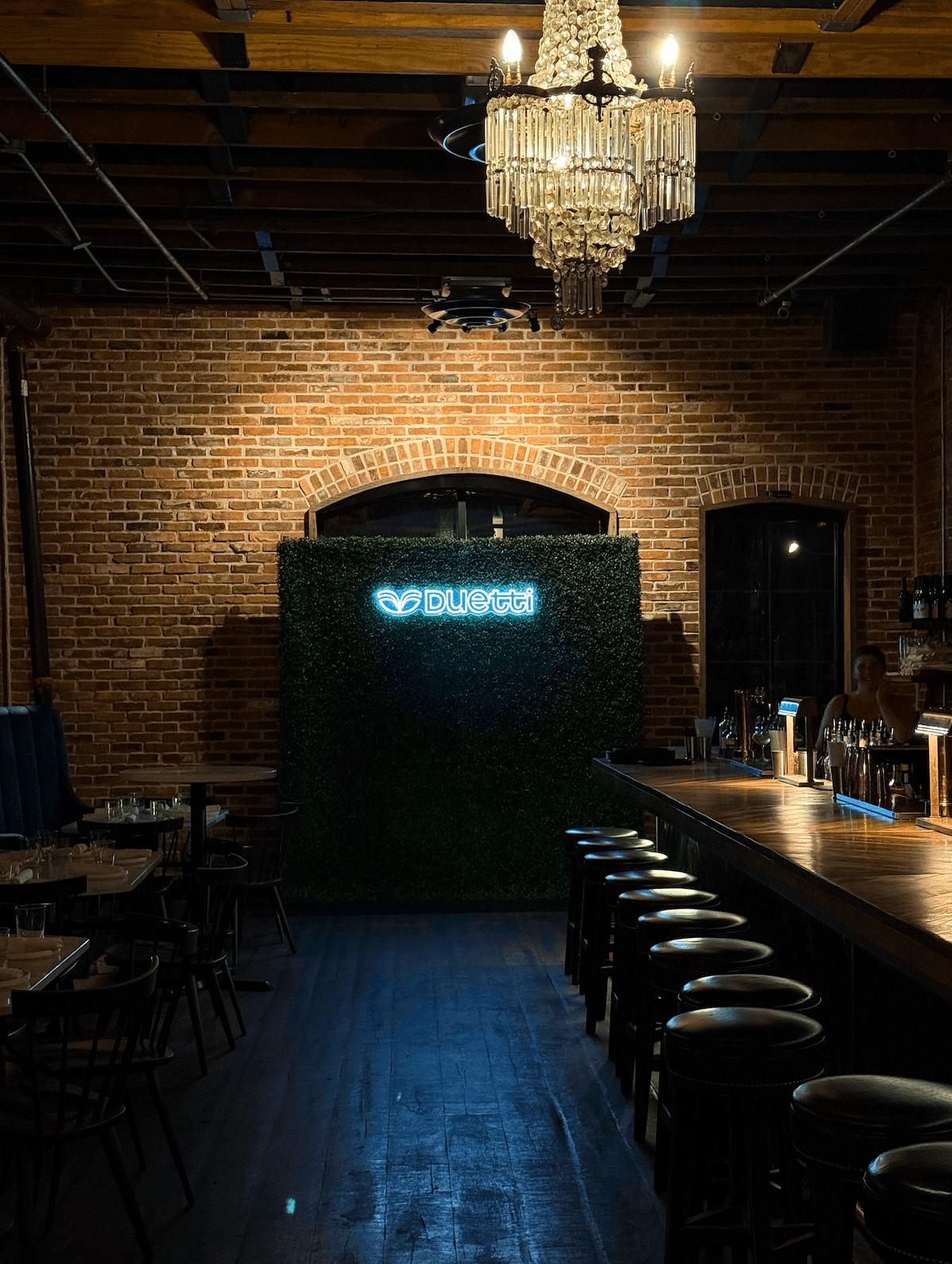 Duetti custom neon logo sign on a greenery wall for a Nashville corporate event