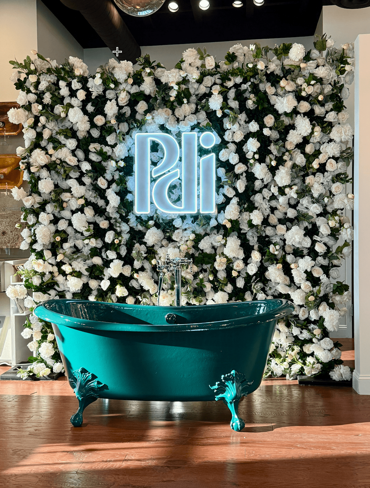 Custom illuminated logo neon sign displayed on a luxury white floral wall for a Nashville corporate event and brand activation.
