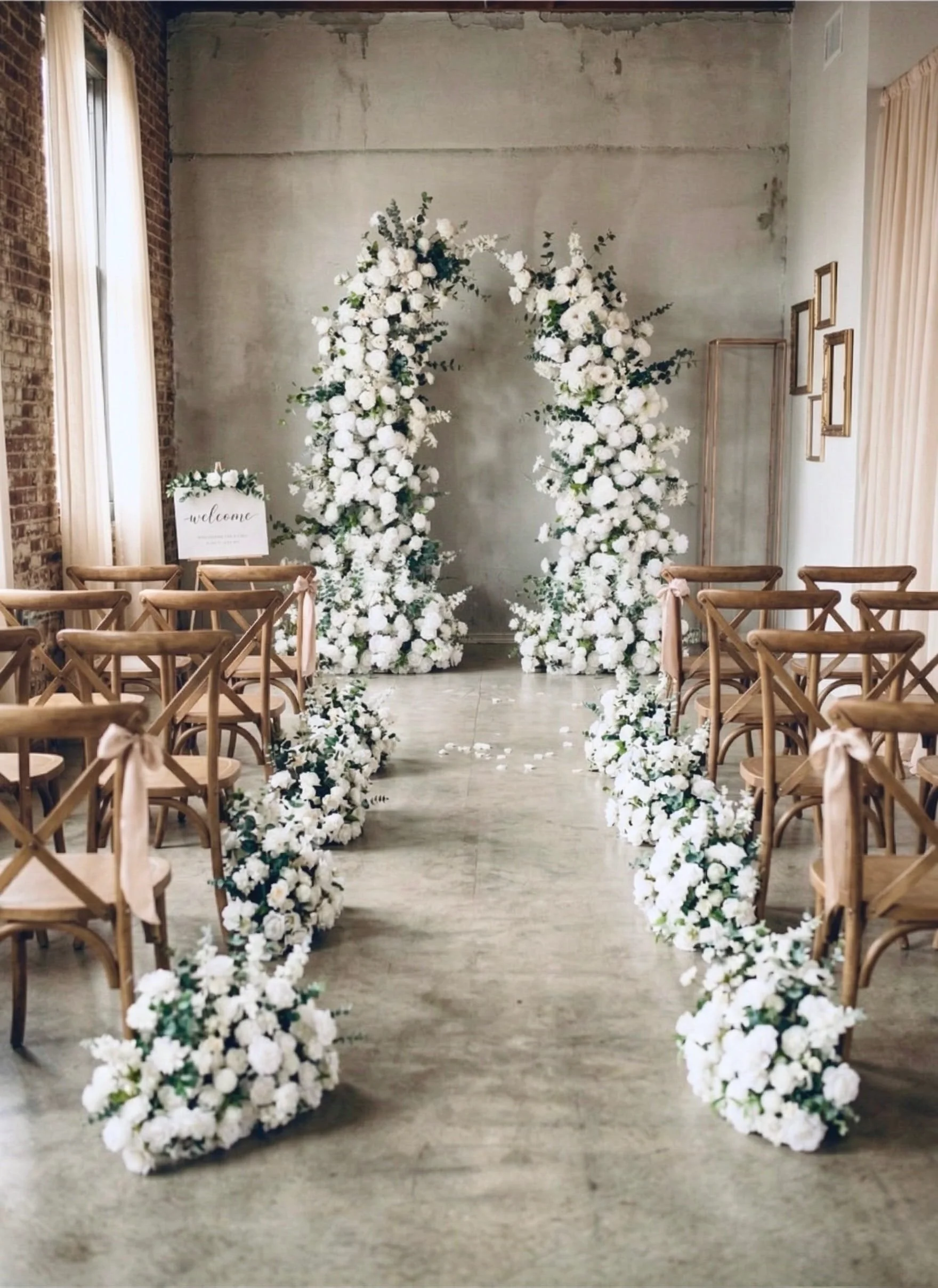 Luxury white silk floral wedding arch with matching floor meadow aisle flowers for a micro wedding at a Nashville industrial venue.