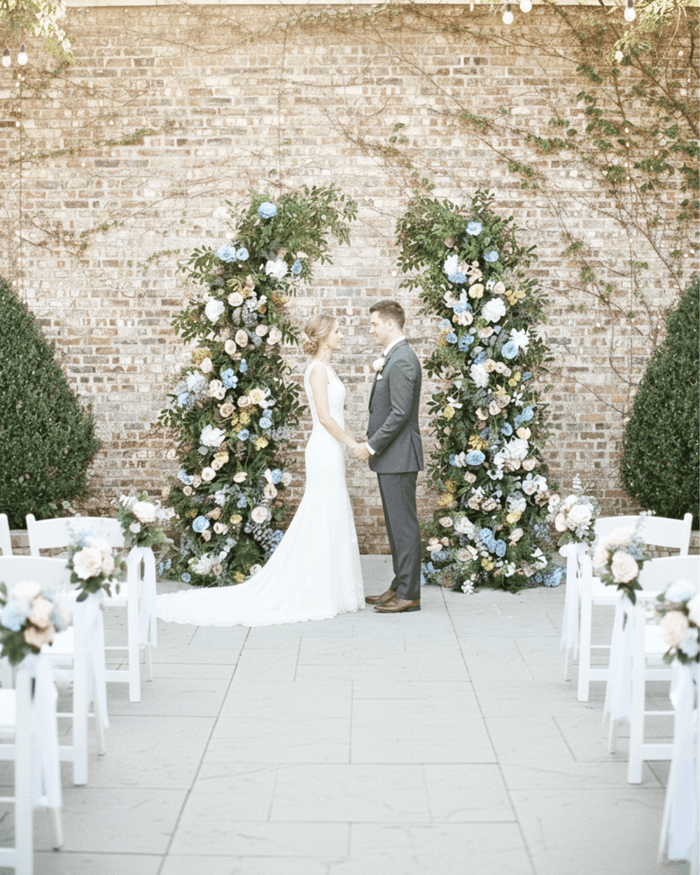 Luxury broken flower arch rental for a Nashville wedding ceremony featuring lush blue and white silk florals against a classic brick backdrop.