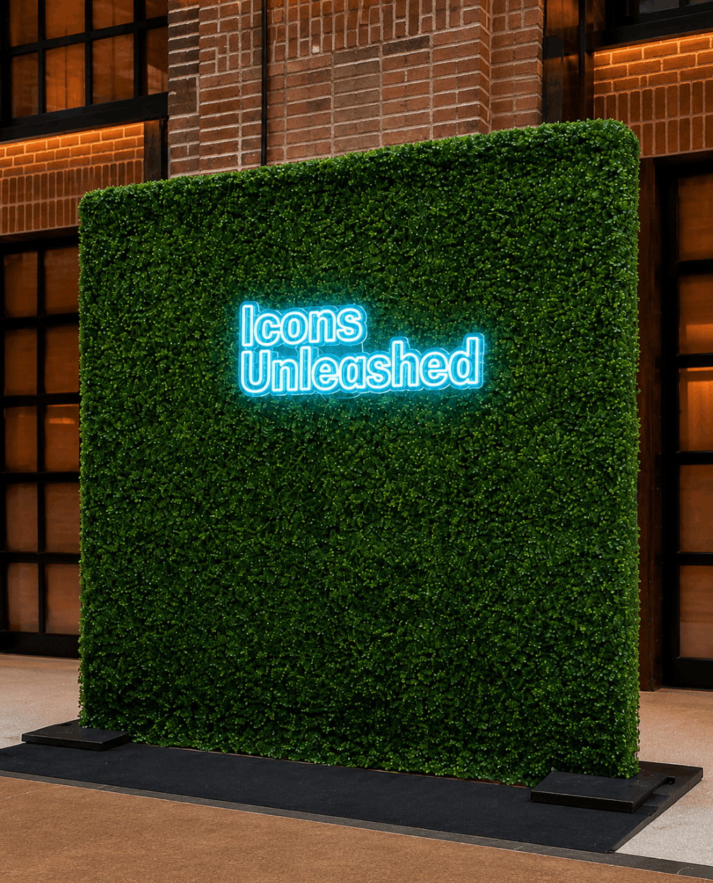 Icons Unleashed custom neon logo sign on a boxwood greenery wall for a corporate sales kickoff in Nashville