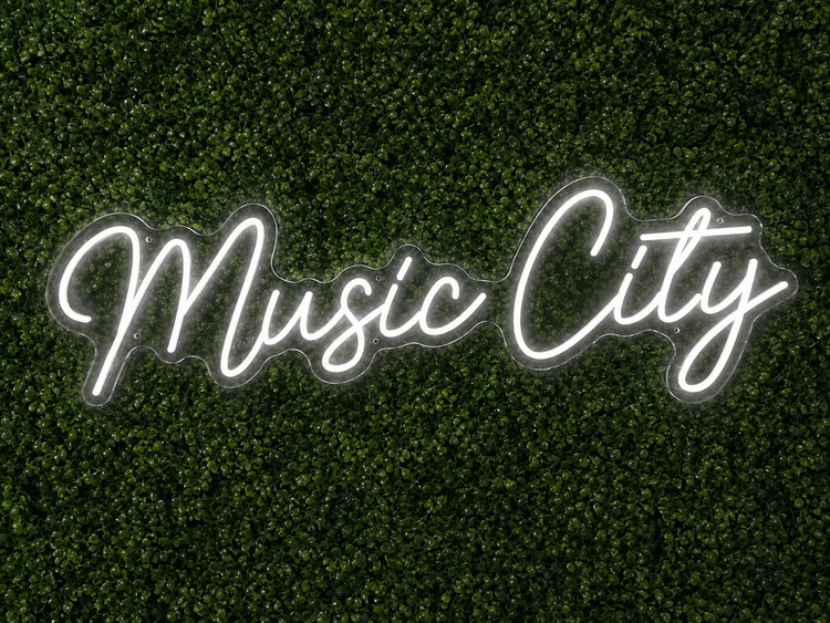 Music City white LED neon sign rental on clear acrylic displayed on a boxwood wall in Nashville