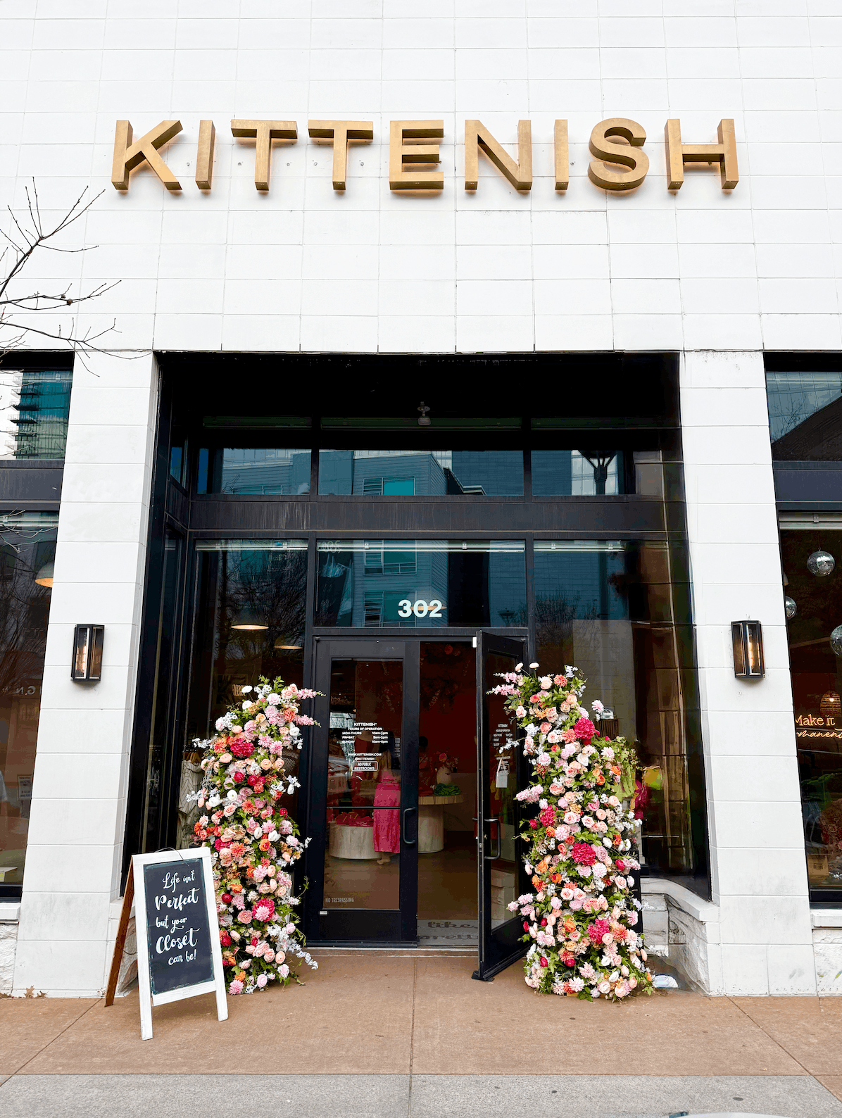 A vibrant Juliet-style floral arch featuring pink, peach, and white roses framing the entrance of the Kittenish boutique in Nashville, created by Flower Walls of Nashville