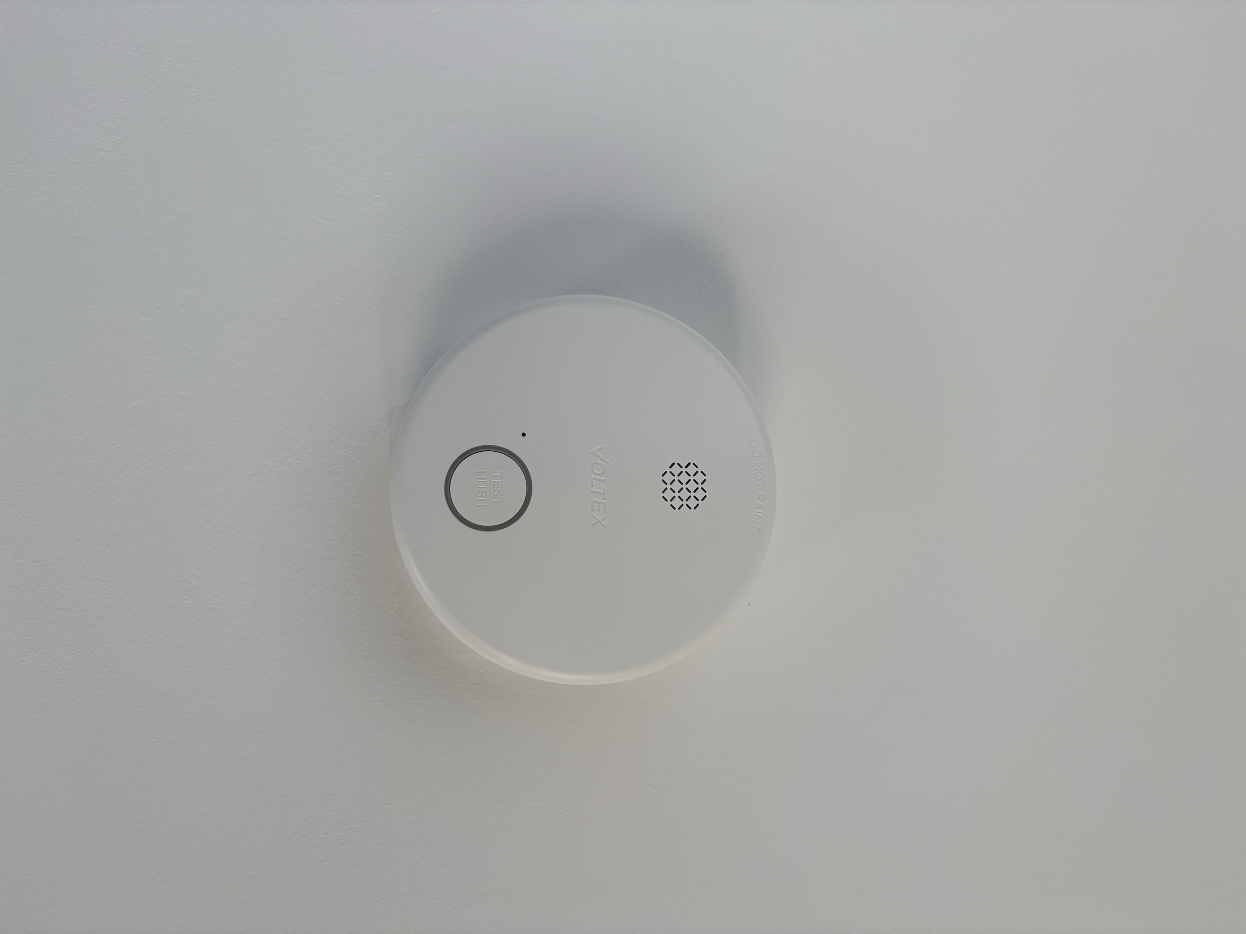A white circular smoke detector mounted on a ceiling