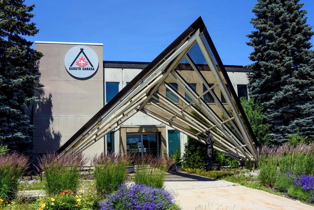 Corporate headquarters front entrance with professional landscape design, featuring modern planting beds, walkways, and greenery that improve brand image and client perception.