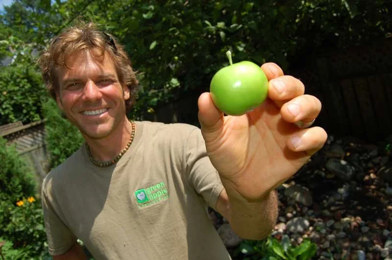 Portrait of Peter Solti, founder of Green Apple Landscaping, holding a green apple symbolizing the company’s early beginnings