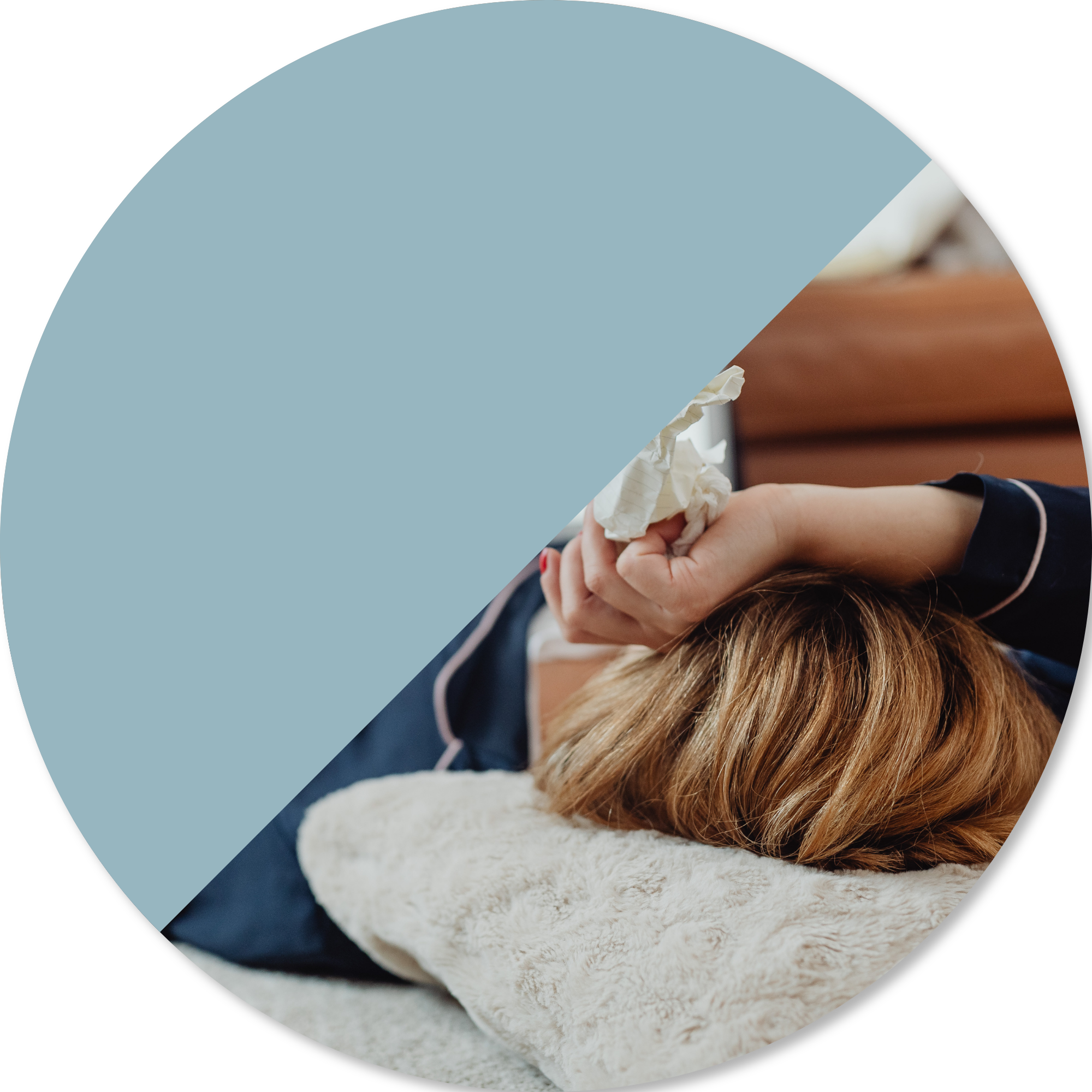 A person resting on a couch holding tissues, representing the impact of fatigue, low energy, and the need for rest and recovery