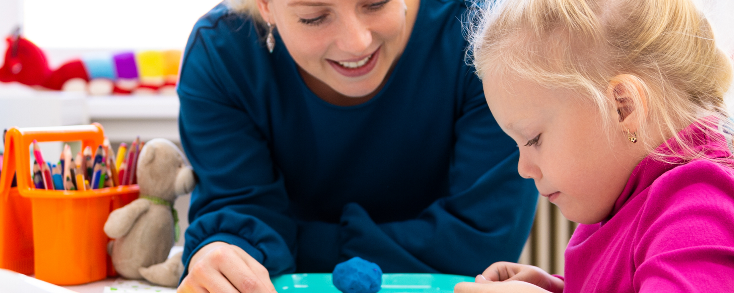 Paediatric occupational therapist supporting a young child during a play-based therapy activity at a table