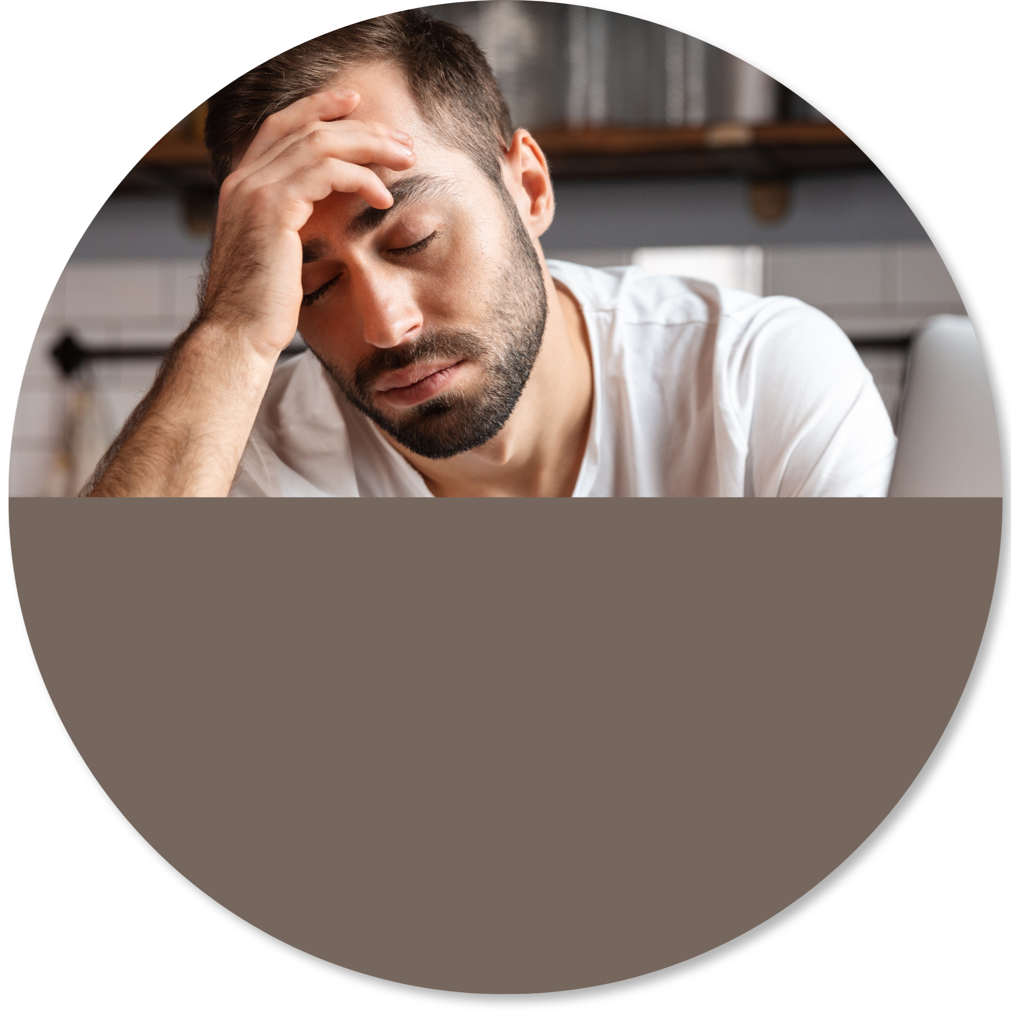 A man with short brown hair and a beard, resting his forehead on his hand with eyes closed, appearing to feel stressed or tired, indoors with a blurred background.