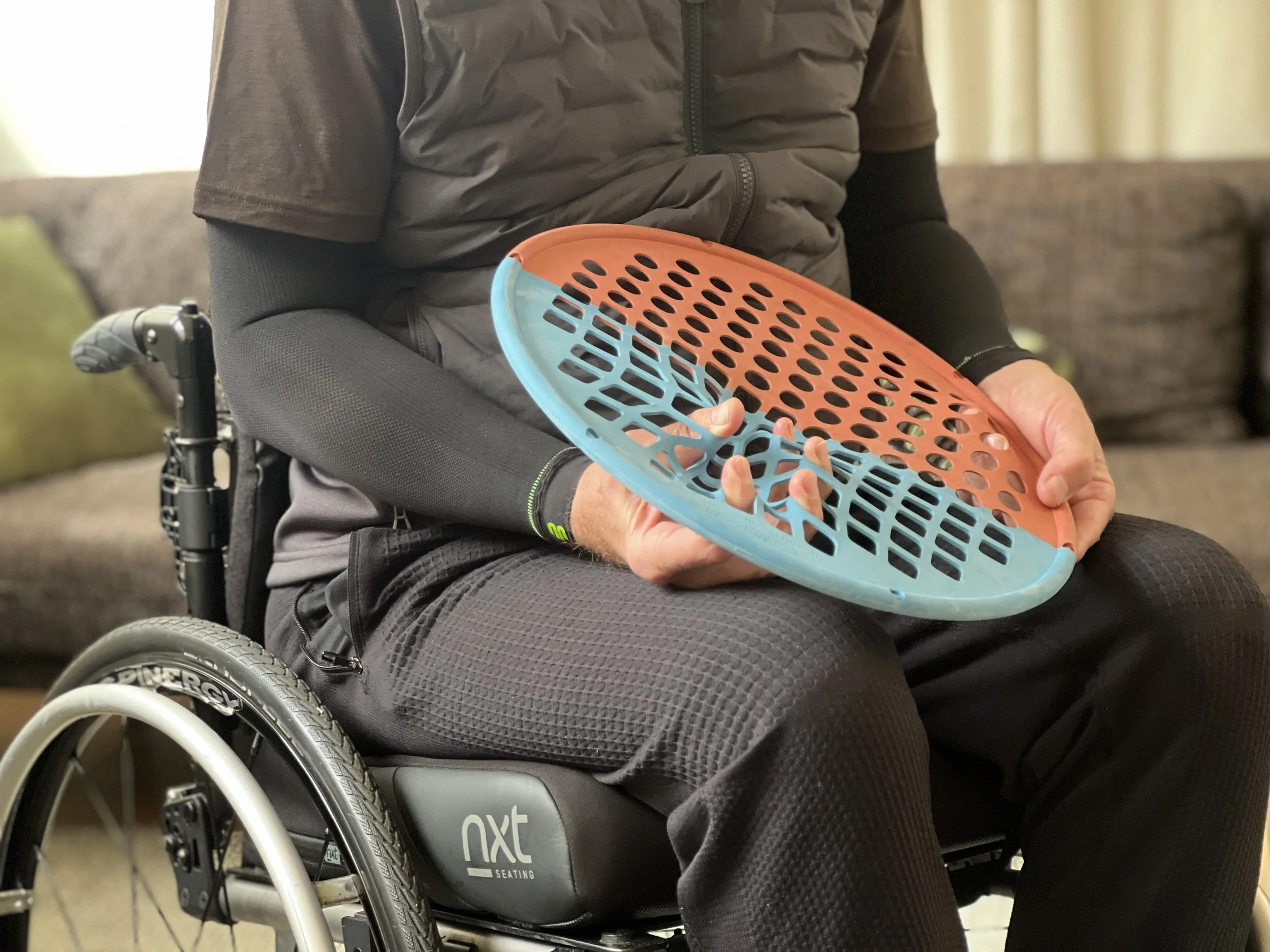 Man using a Power-Web hand exerciser during hand rehabilitation after a spinal cord injury to improve grip strength, dexterity and upper limb function.