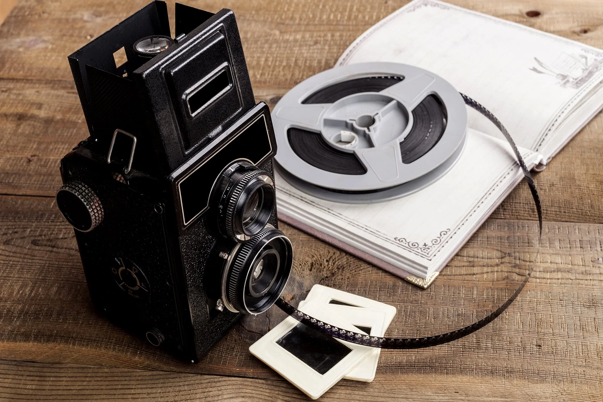 Old style camera with film reel lying on a notebook.