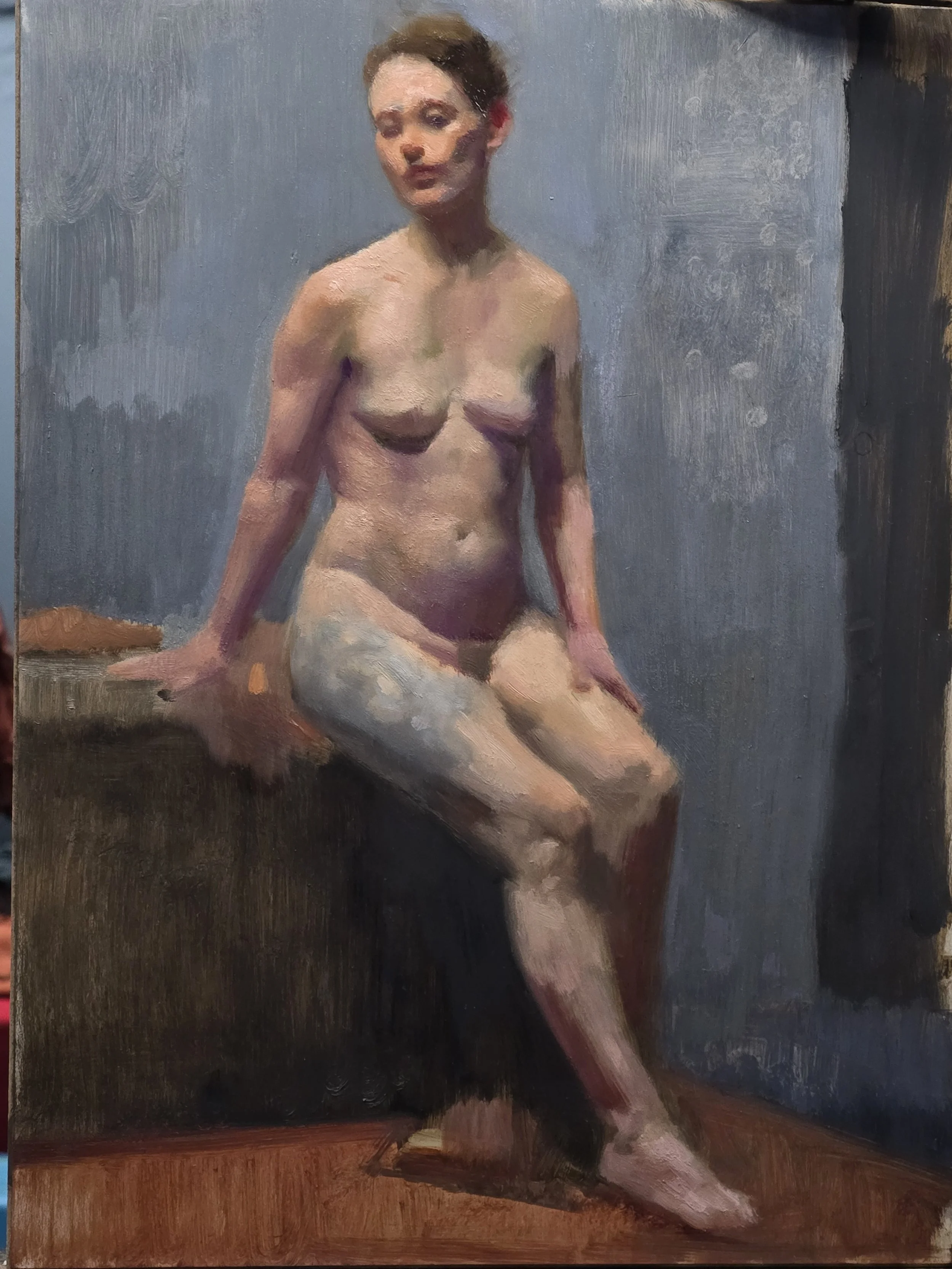An oil painting from art class of a nude woman with short hair sitting on a wooden surface, with one hand resting behind her and the other on her knee. She is looking slightly to her left, against a grayish background.