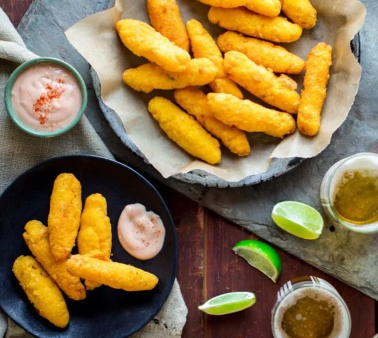 Basket of fried fish fillets with lemon wedges and dipping sauces