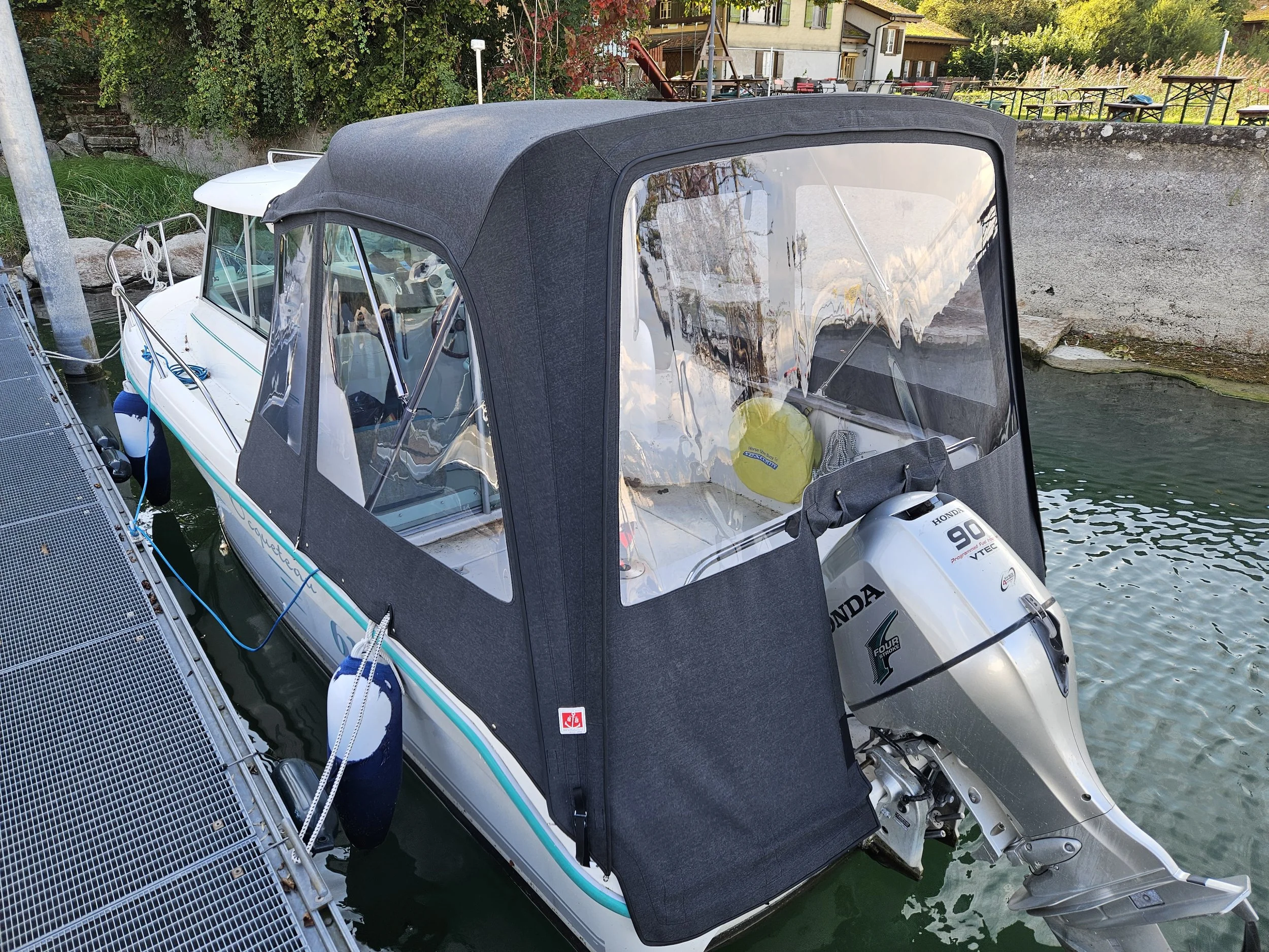 Motorboot mit Schutzverdeck und Honda Aussenbordmotor am Dock befestigt