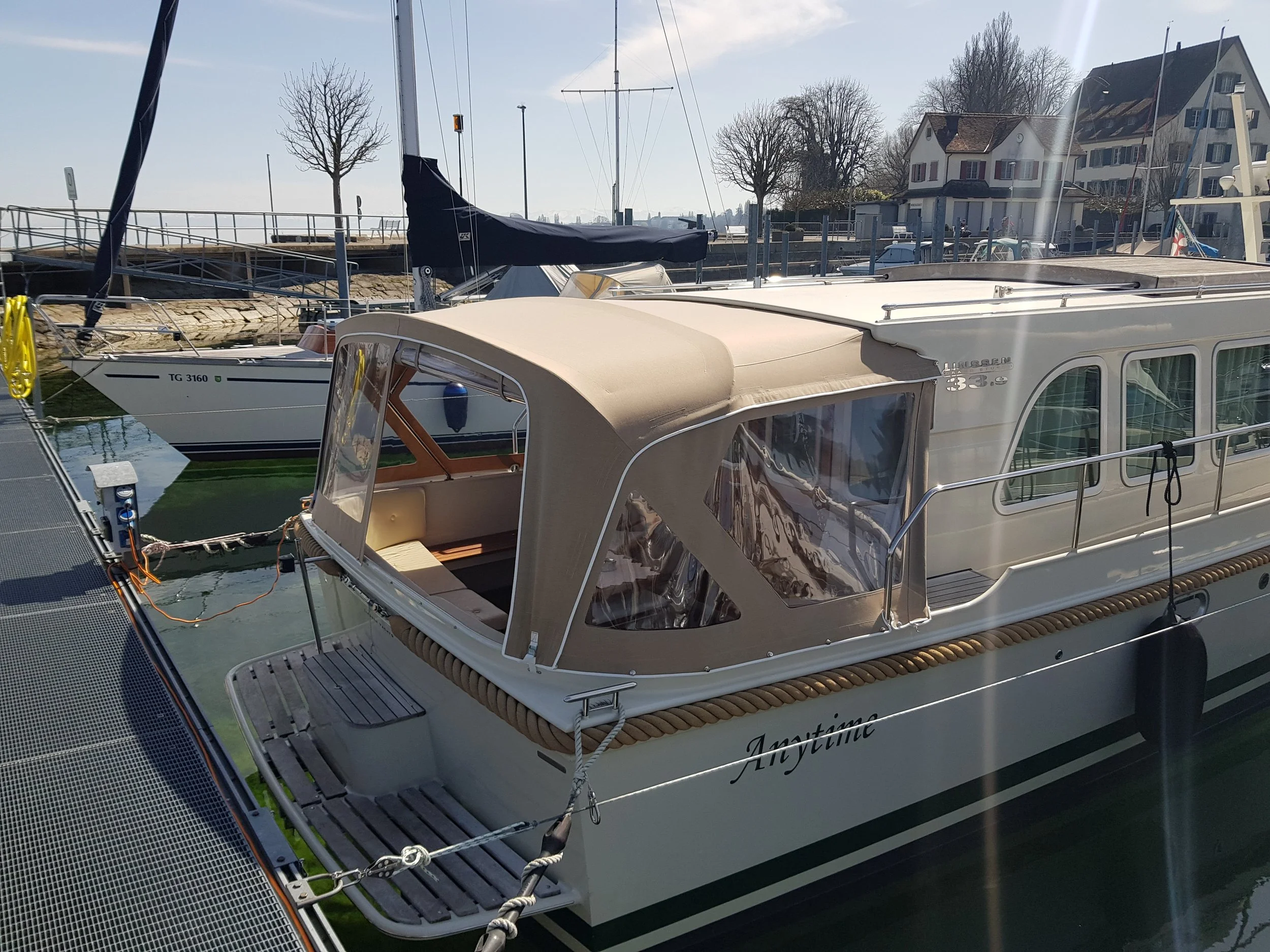 Boot im Hafen vertäut, sonnig, mit modernen Gebäuden im Hintergrund.