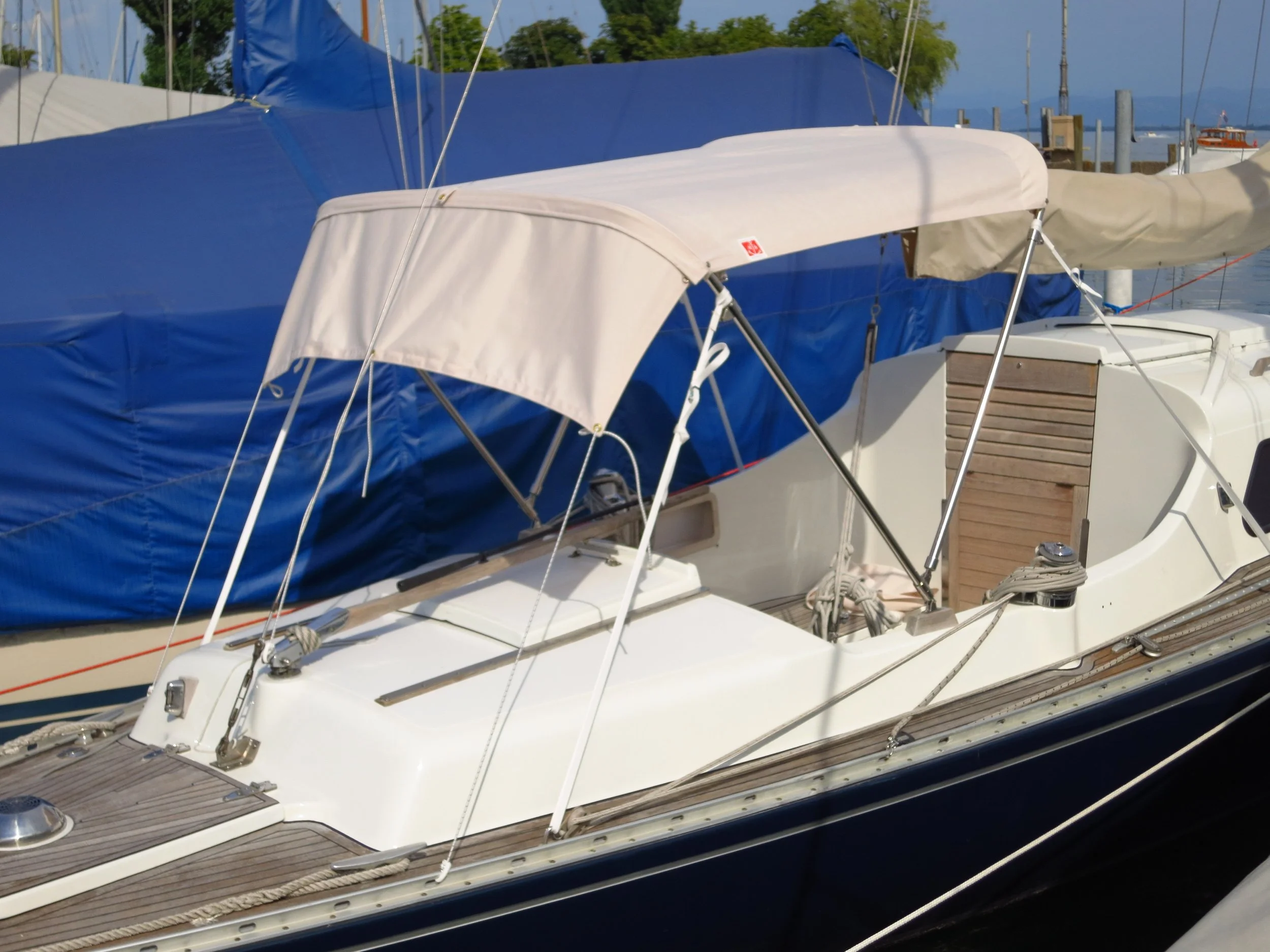 Segelboot mit Sonnenschutz auf einer Anlegestelle, umgeben von anderen Booten.