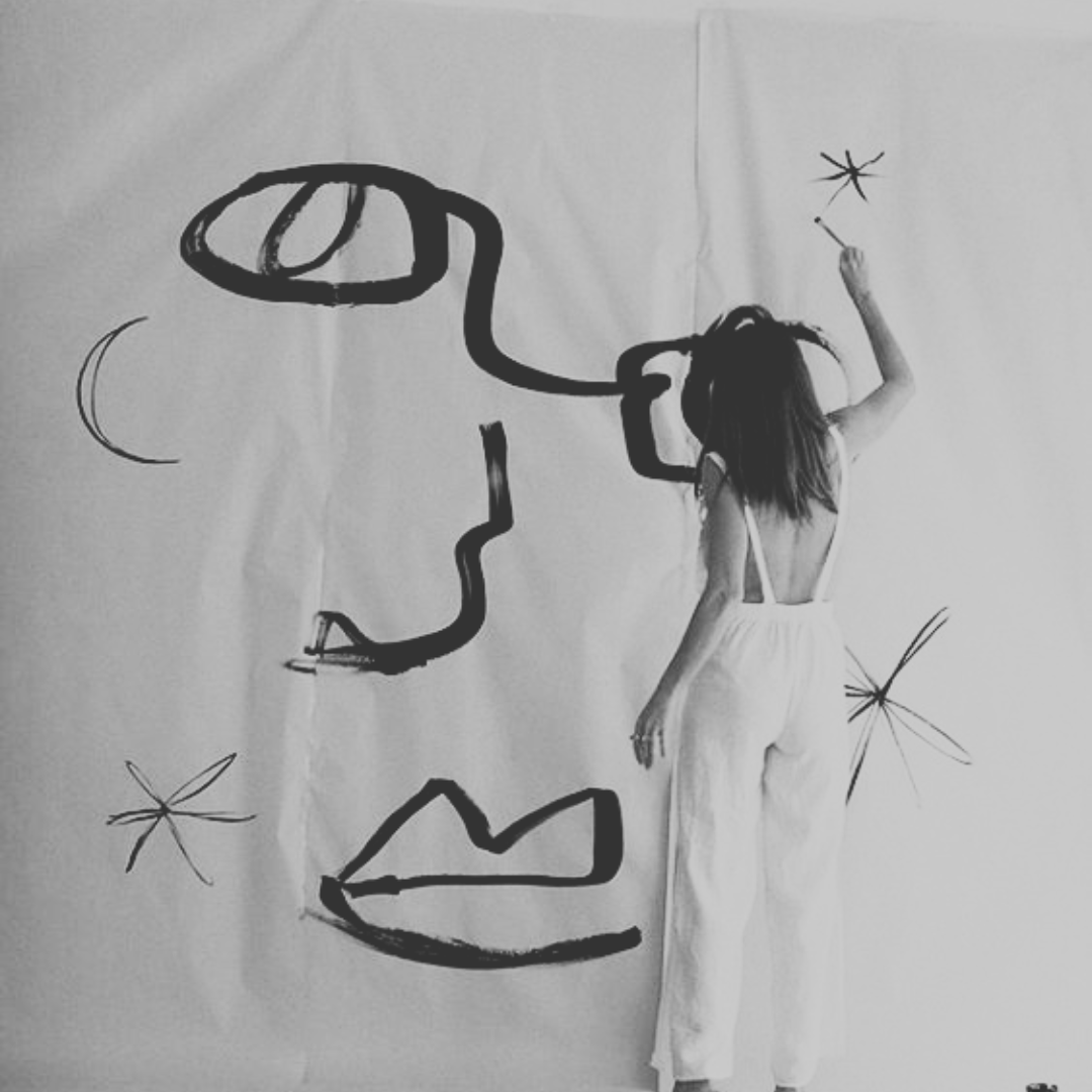 Immagine in bianco e nero, donna di spalle che dipinge un viso astratto
