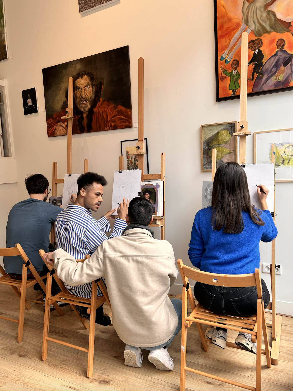 A small group of stβArt participants seated at easels, actively sketching and sharing feedback during art classes, workshops, and team building activities in Amsterdam.