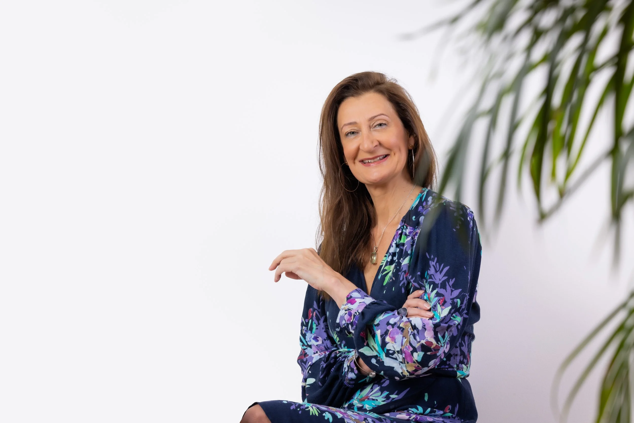 a woman in a navy top witting next to a green plat in her Executive headshot photography session