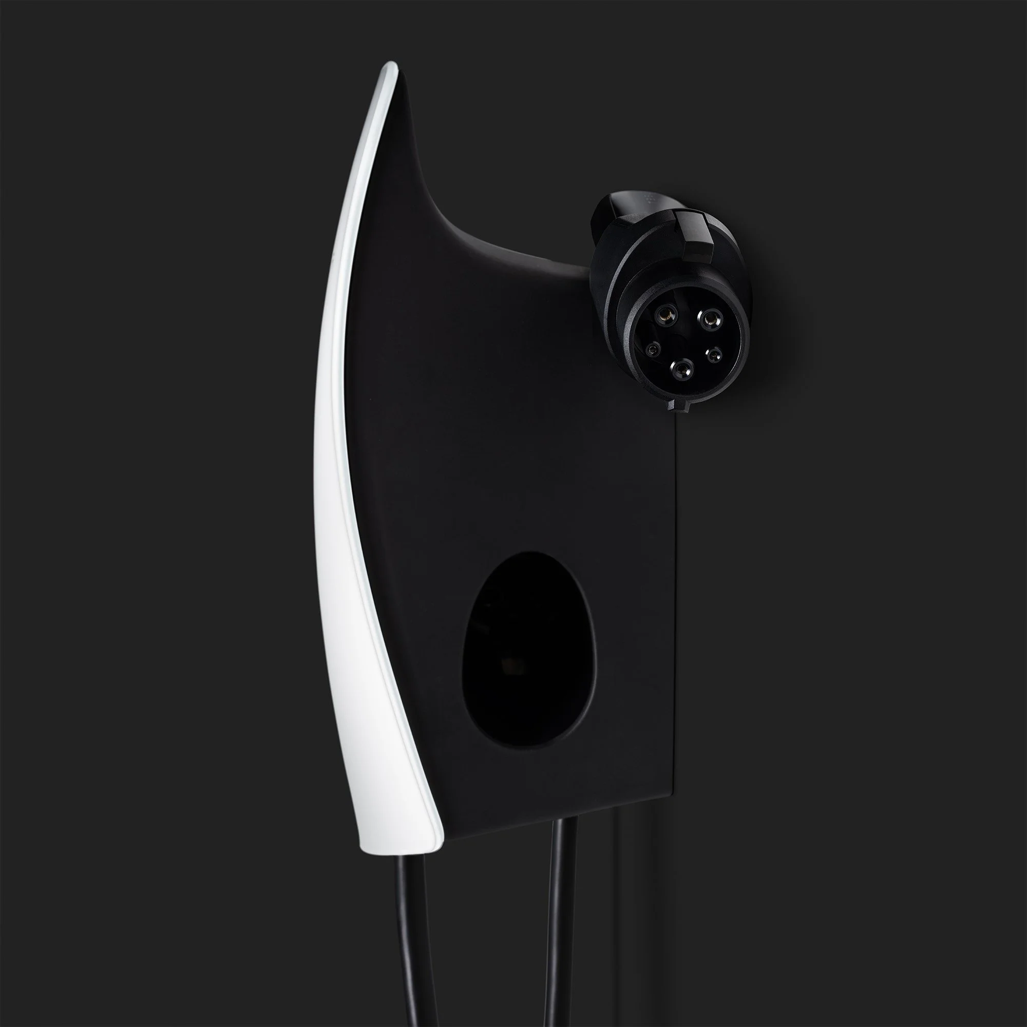 A close-up of an electric vehicle charging station with a black and white design on a dark background.