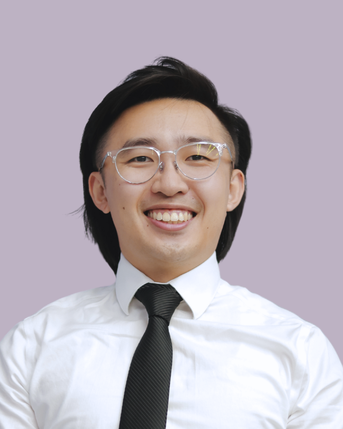 A young man with black hair, glasses, wearing a white shirt and black tie, smiling against a light purple background.