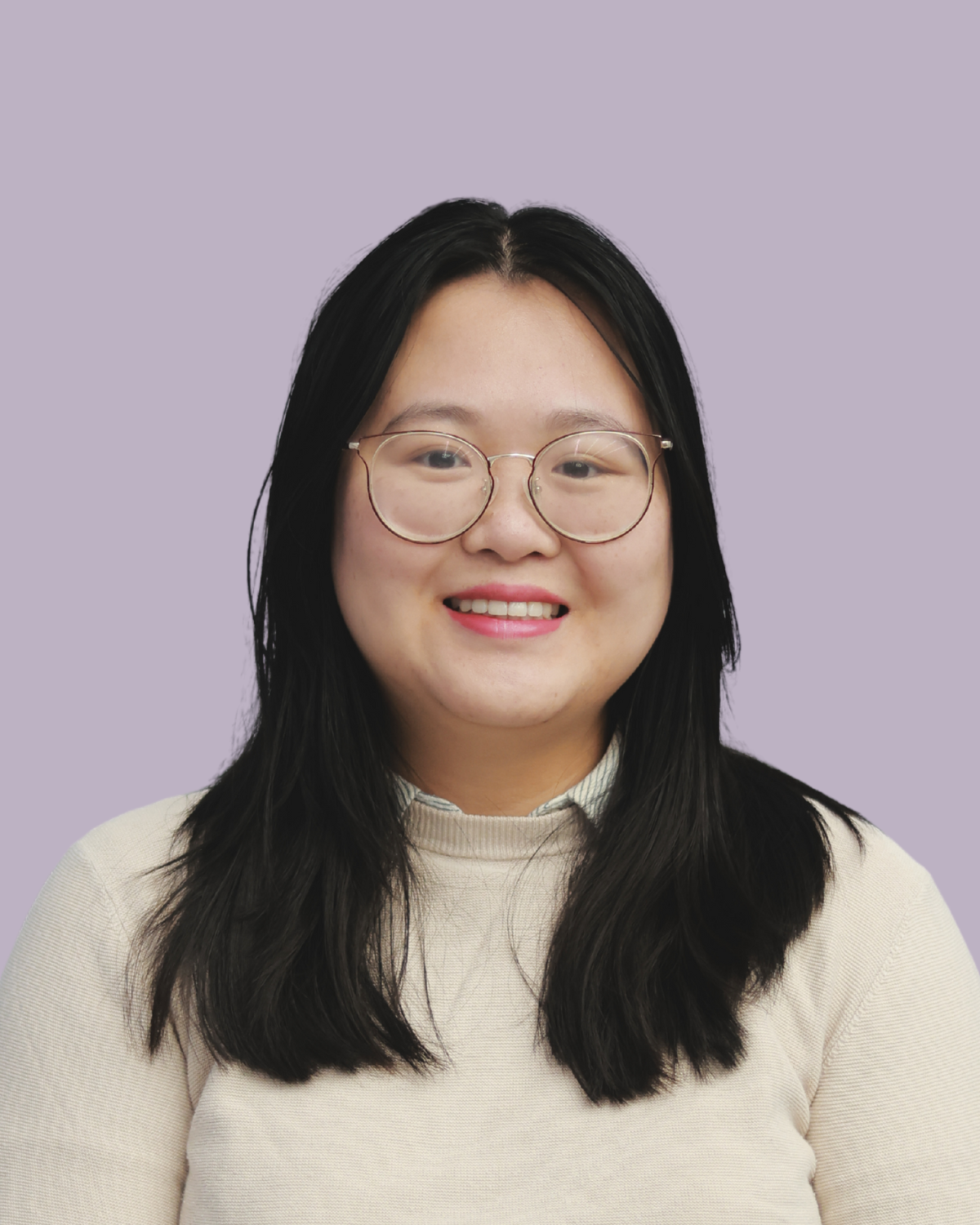 A young woman with black hair, wearing round glasses and a beige top, smiling against a light lavender background.