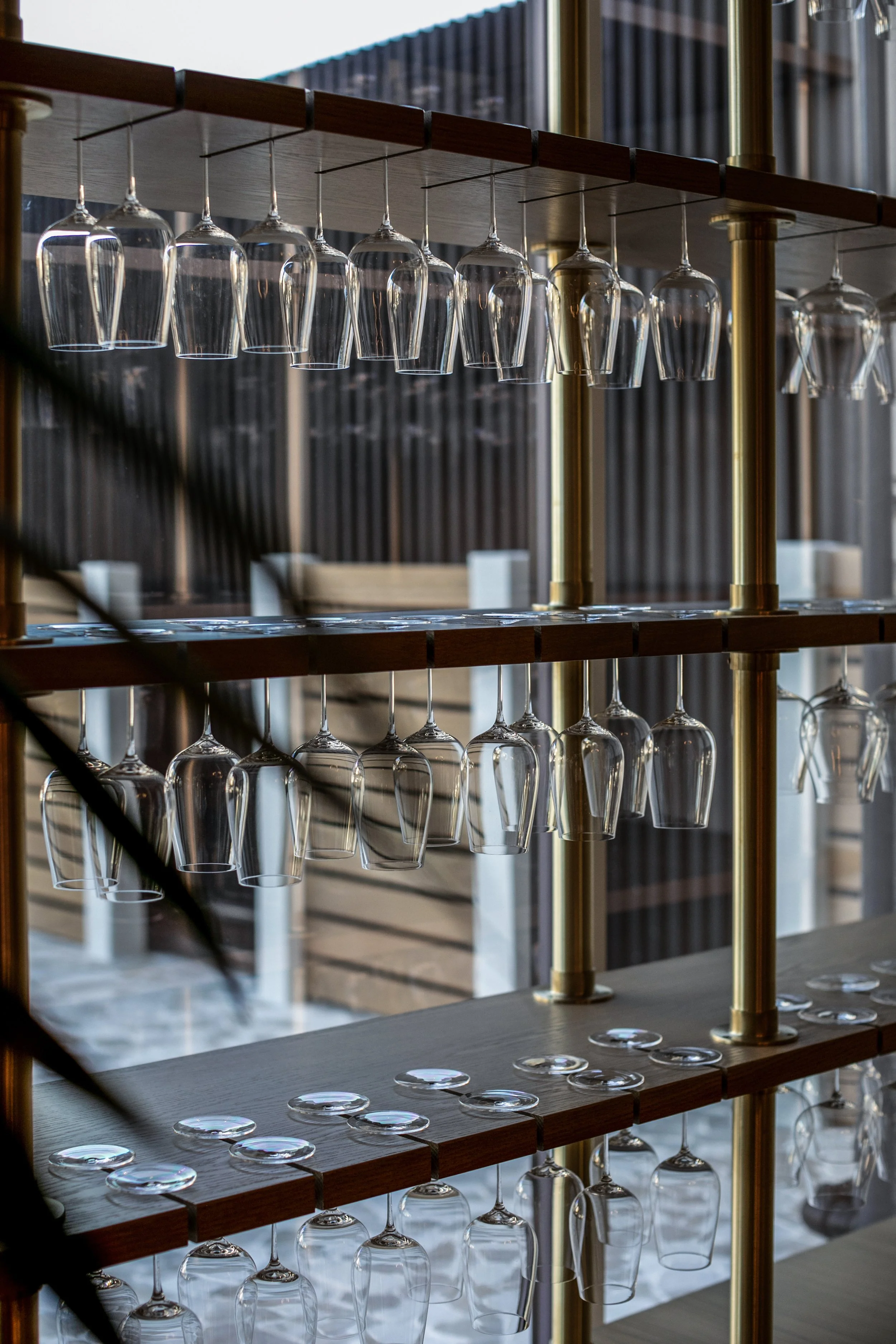 Glassware storage shelf with upside-down wine glasses hanging upside down and additional glasses on shelves.