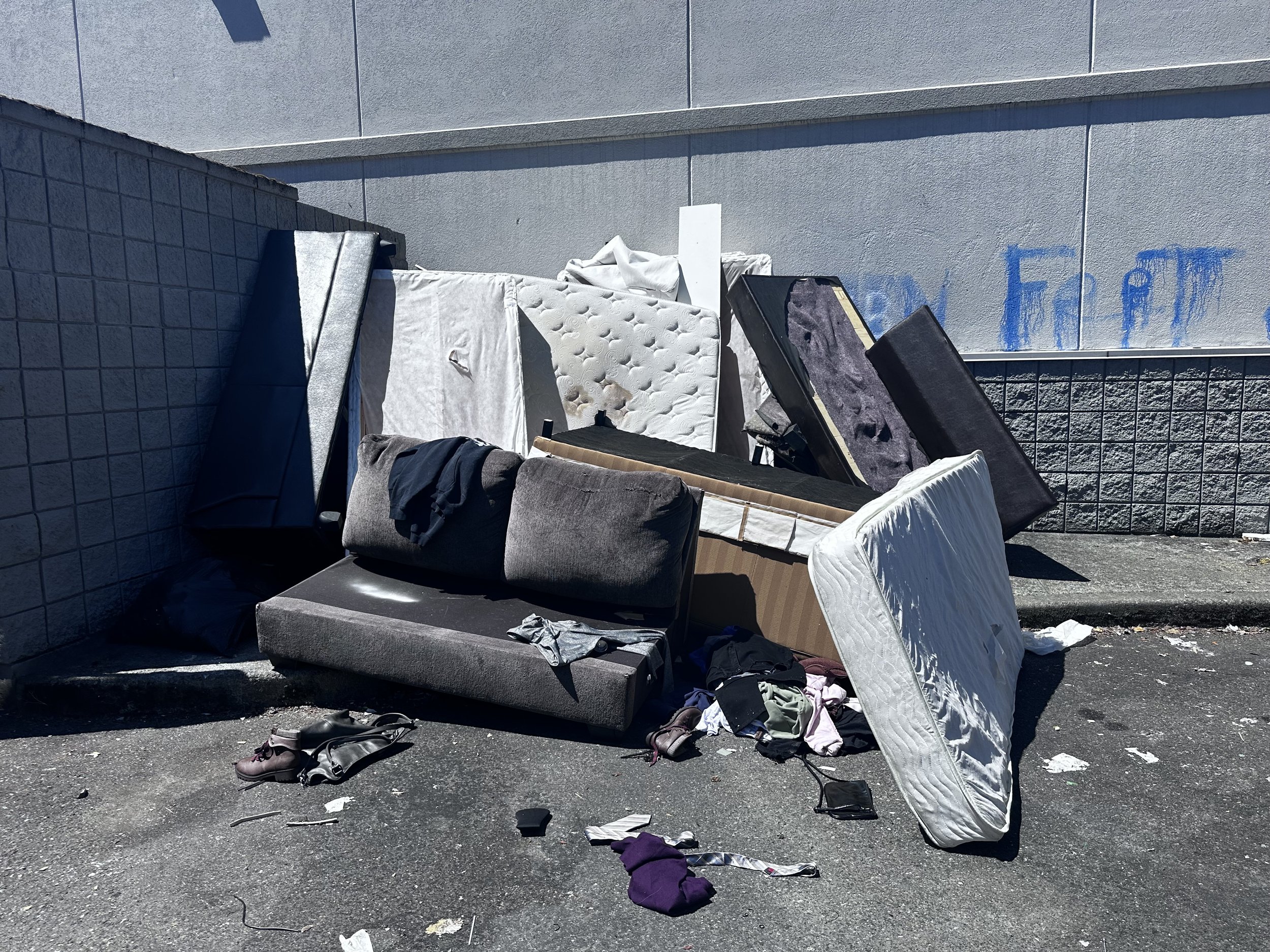Discarded mattresses, couch, furniture, and household debris at a Puyallup commercial property before junk removal.