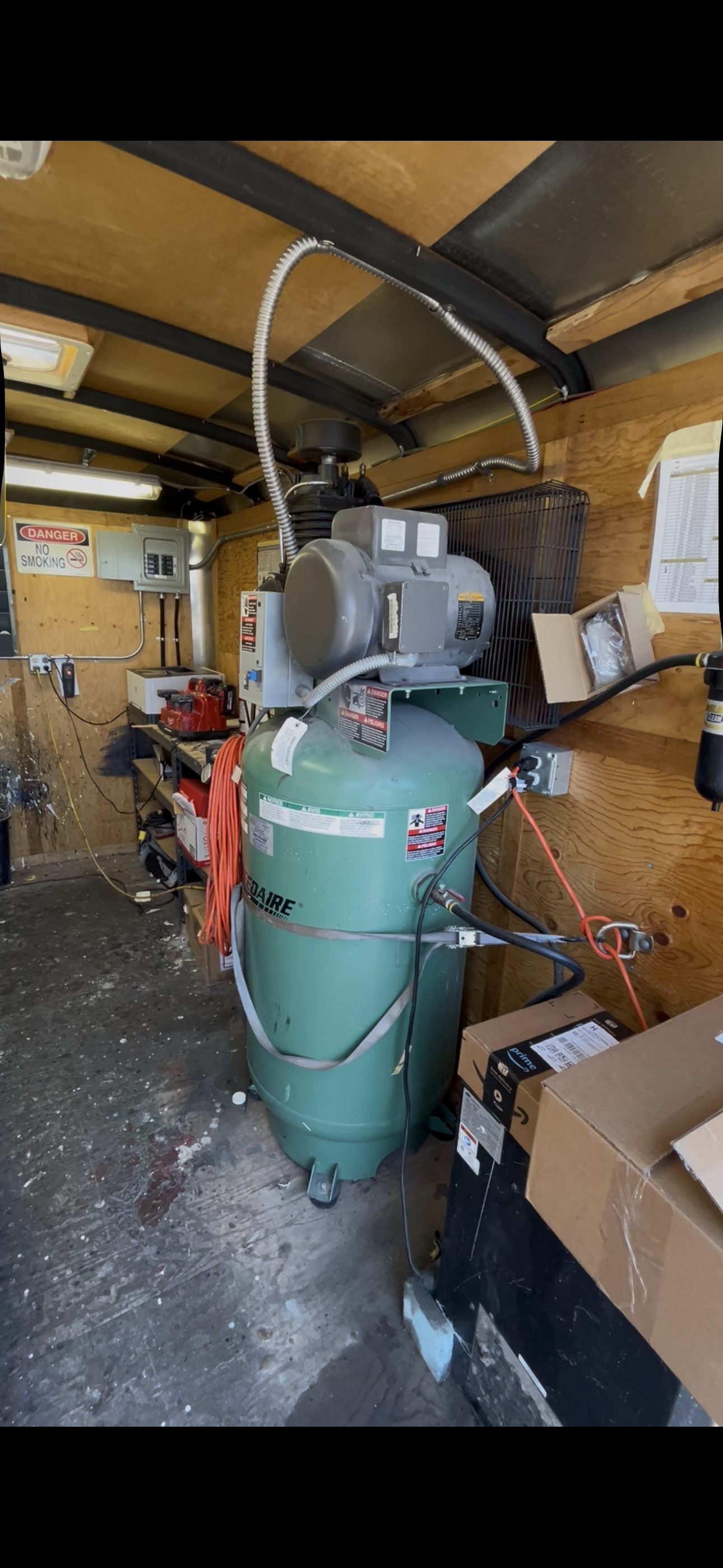 Large green industrial air compressor installed inside an automotive shop equipment room at Dent Wizard in Tukwila, WA.