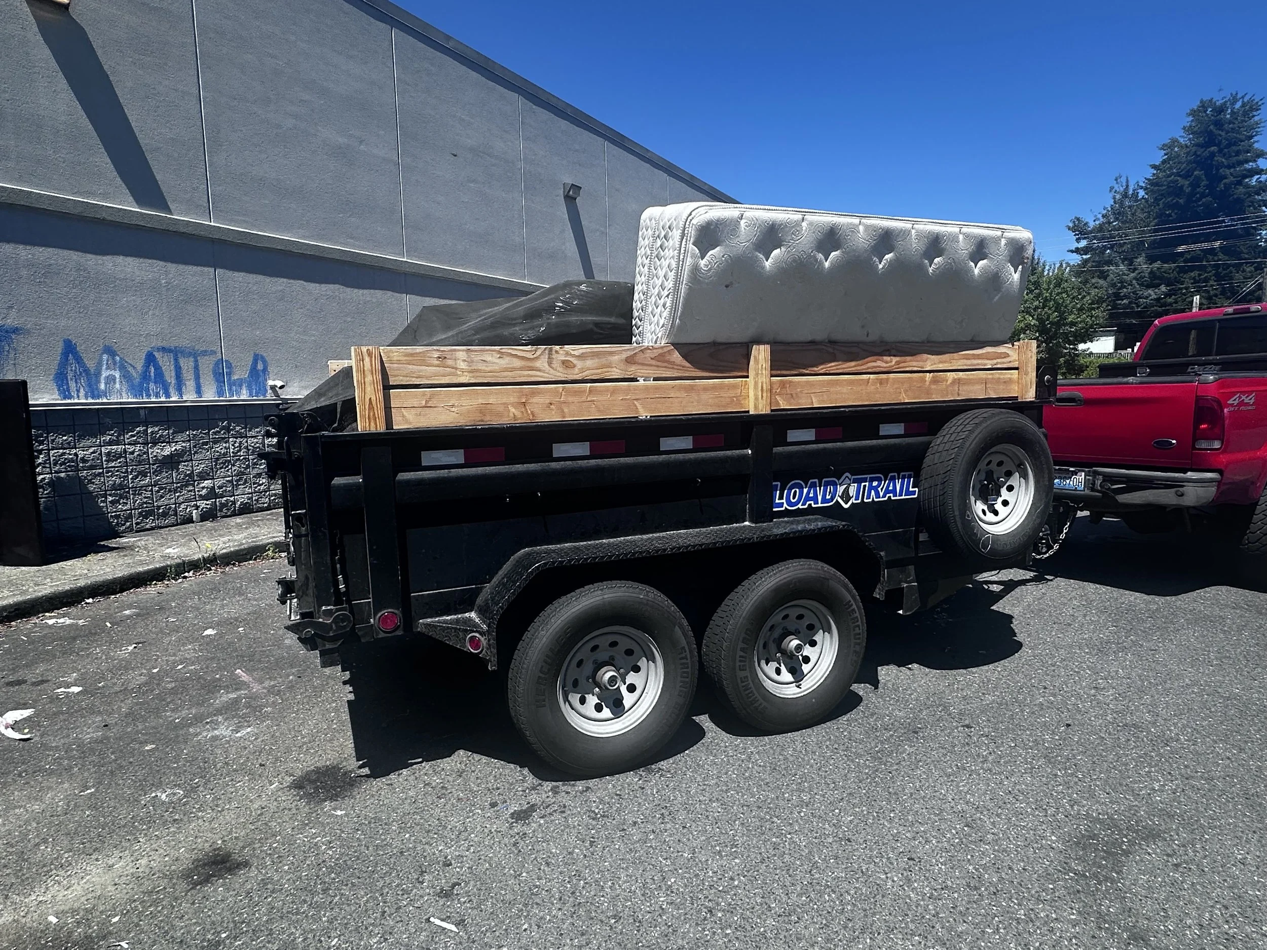 Dump trailer loaded with mattresses and discarded furniture during commercial illegal dumping cleanup in Puyallup.