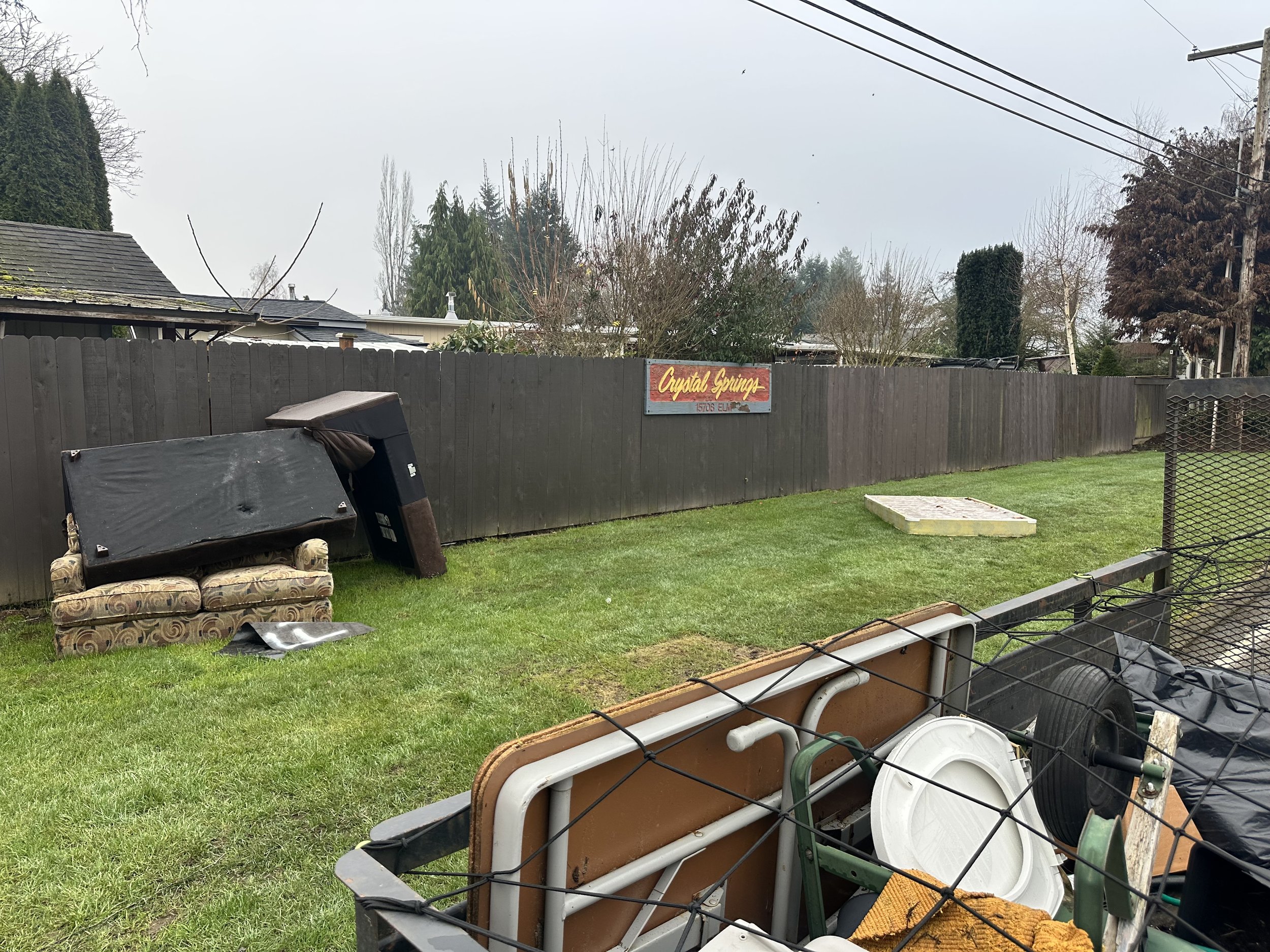 Commercial property lawn with illegally dumped furniture and debris before junk removal cleanup in Seattle WA.