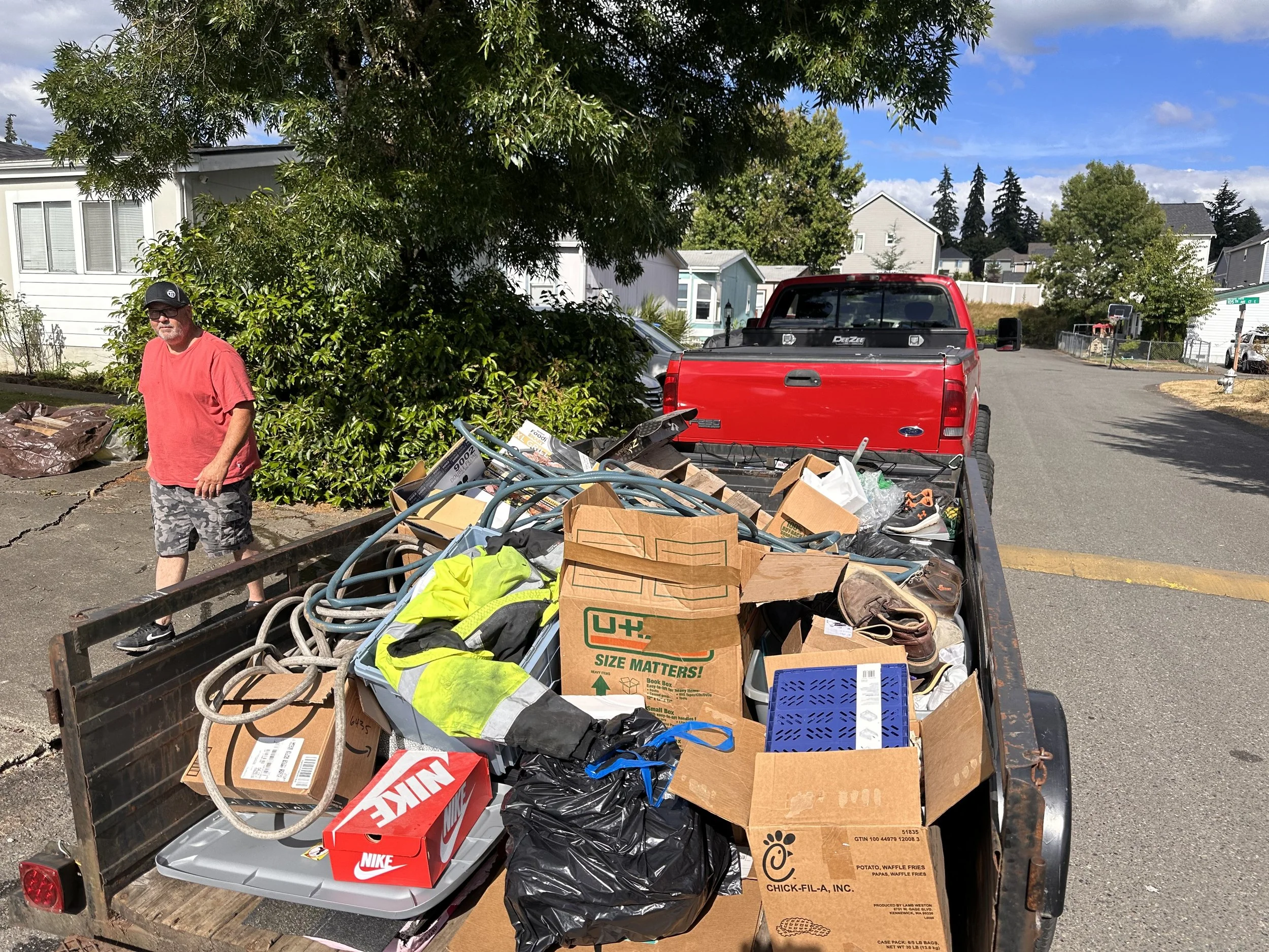 Utility trailer loaded with cardboard boxes, bagged trash, wood debris, and miscellaneous household items during a Puyallup junk removal job.