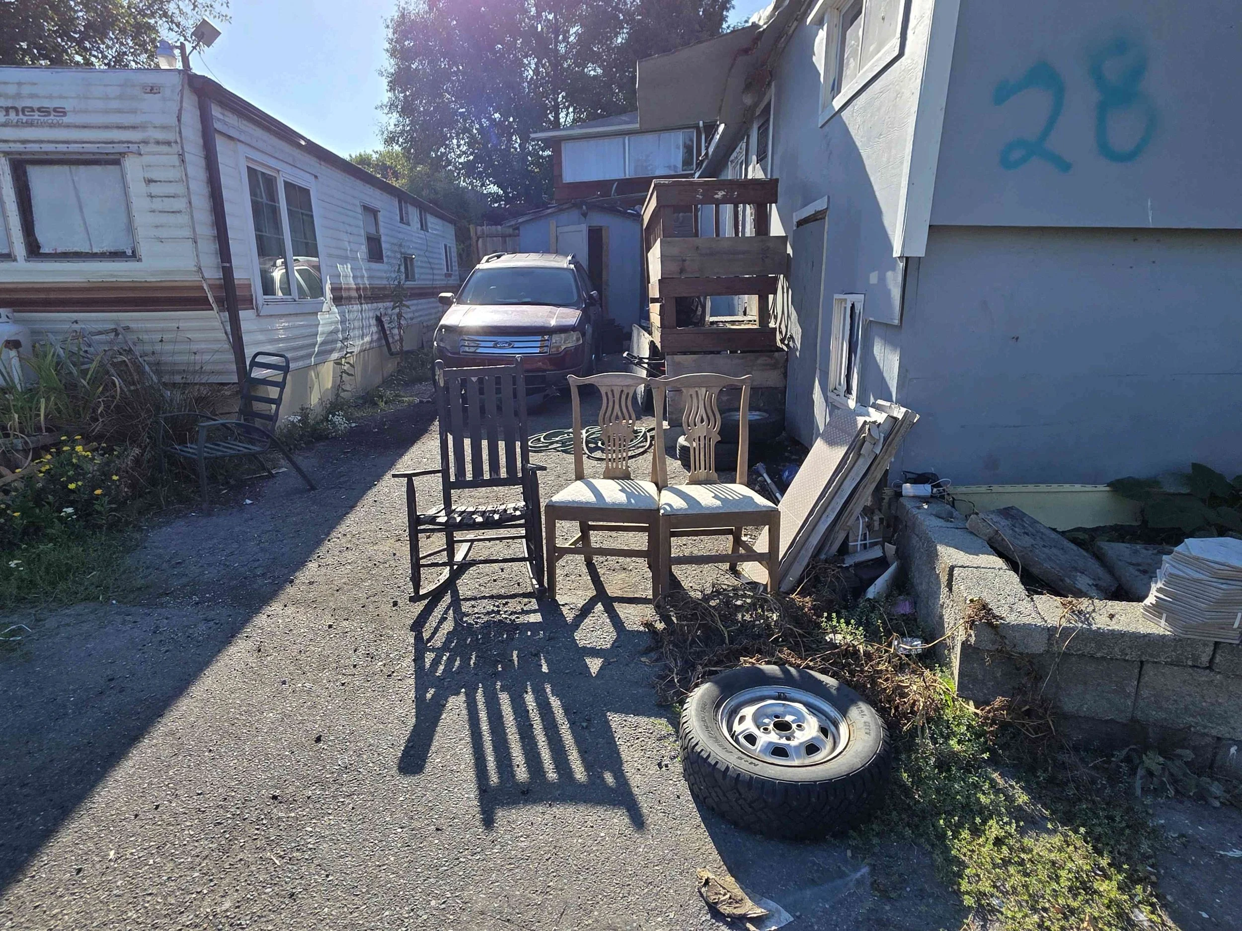 Abandoned chairs, tire, and miscellaneous junk outside a residential property in Tukwila, WA, before an eviction clean-out.