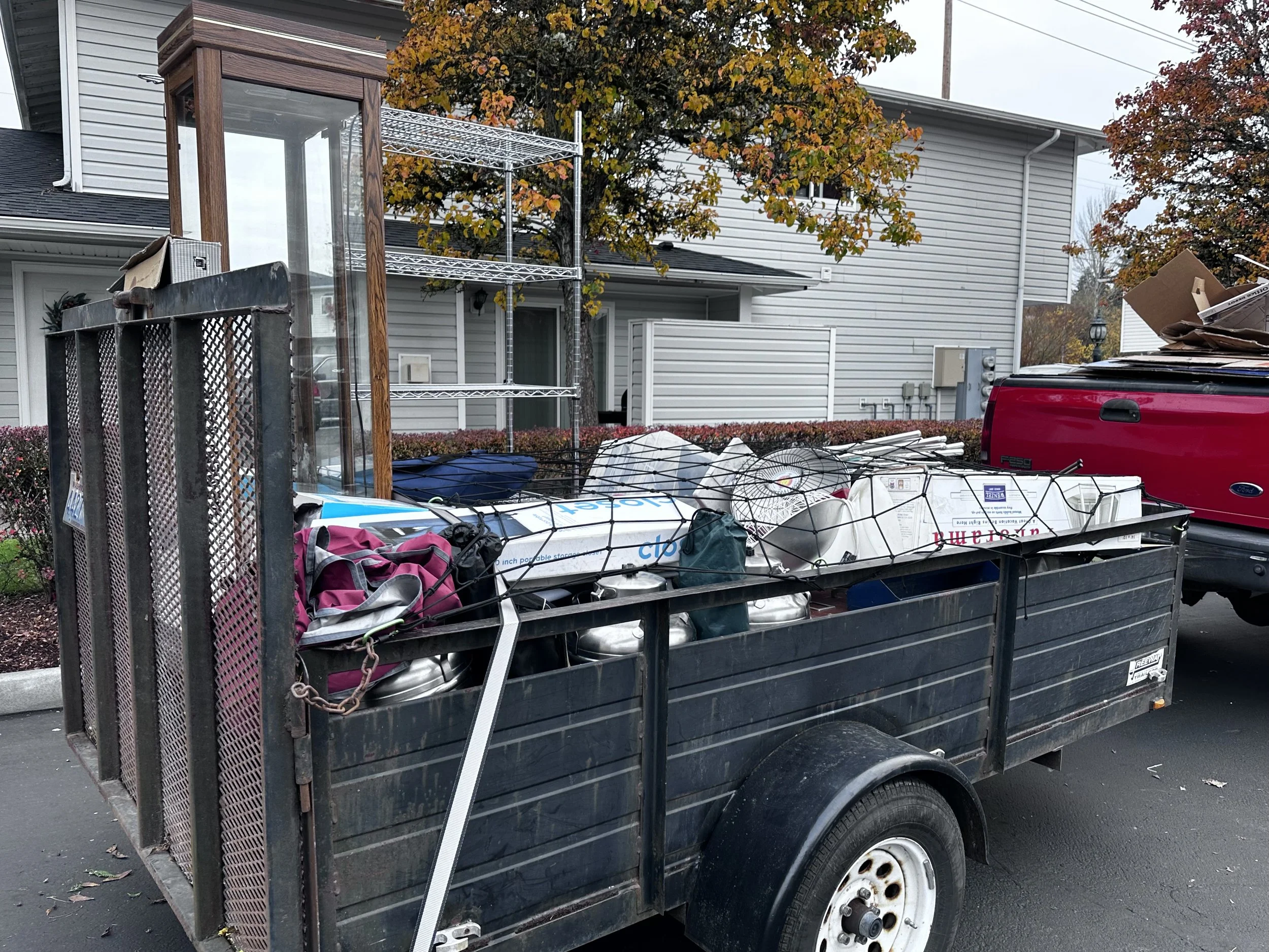 Junk removal trailer loaded with household debris, cardboard, and metal during a multi-load garage cleanout.