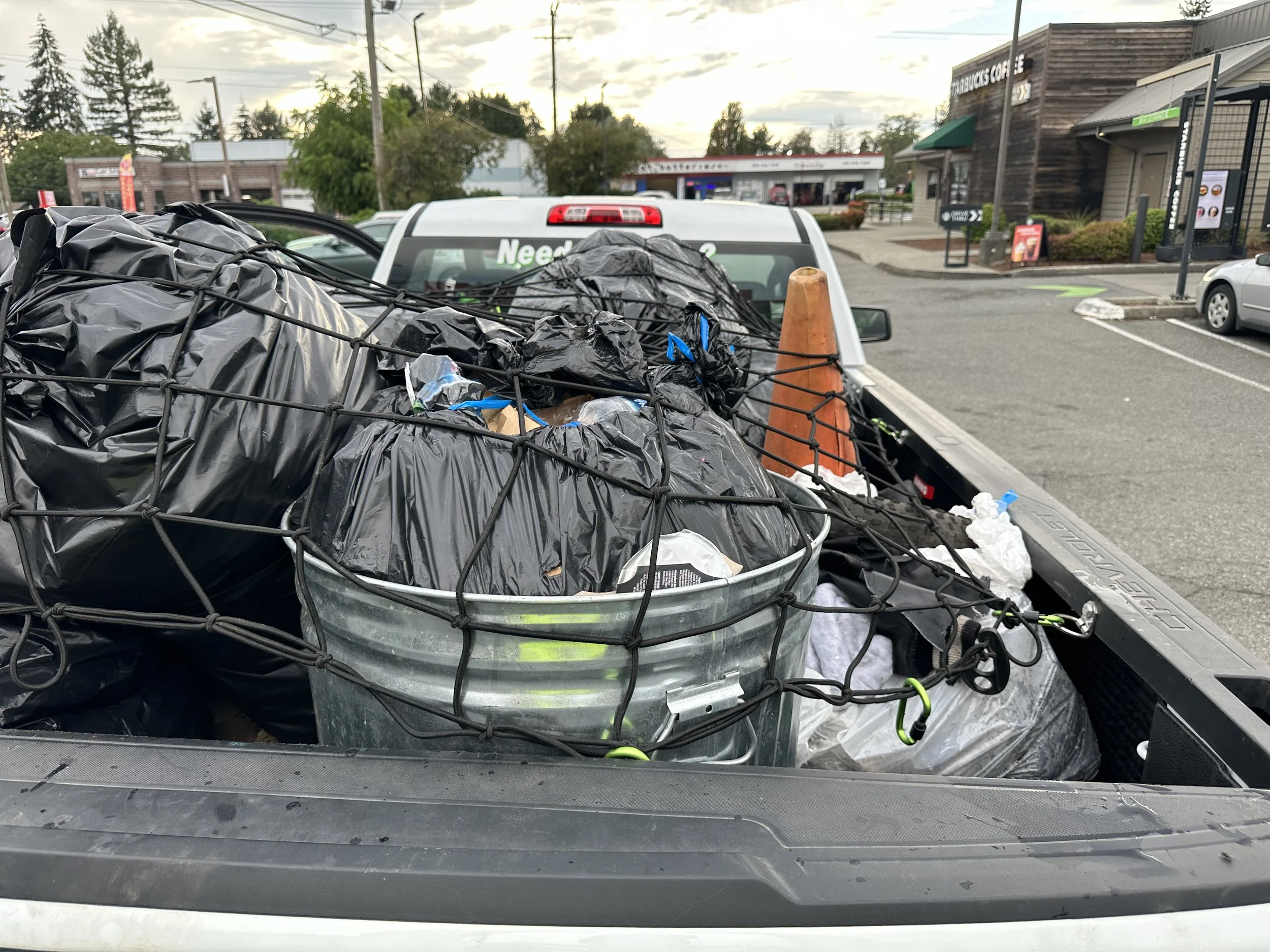 Trash bags secured with a net in galvanized cans inside a truck bed in Seattle.