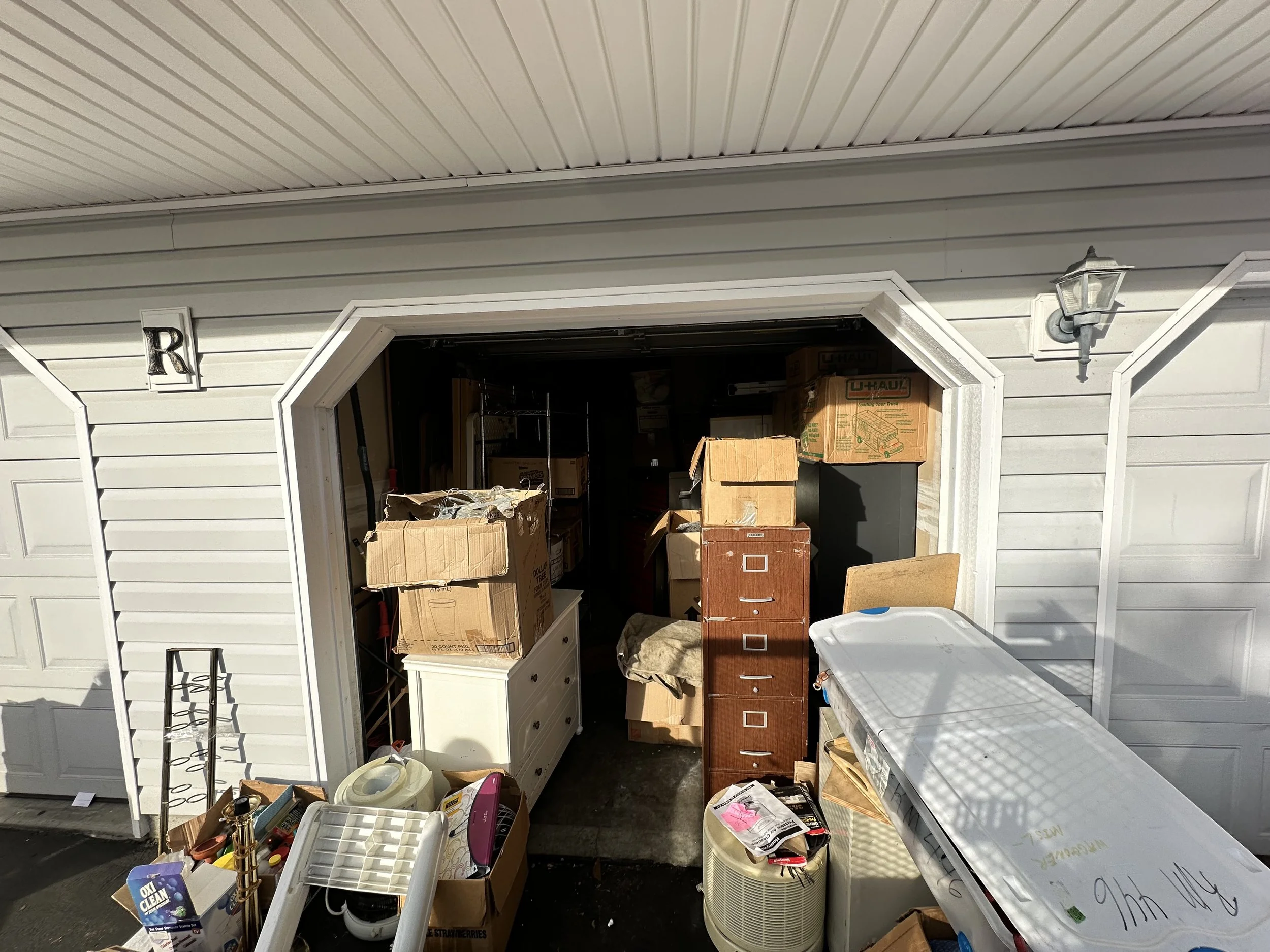 Front of an overfilled garage with piles of boxes and furniture pulled out during a large garage cleanout in Puyallup.