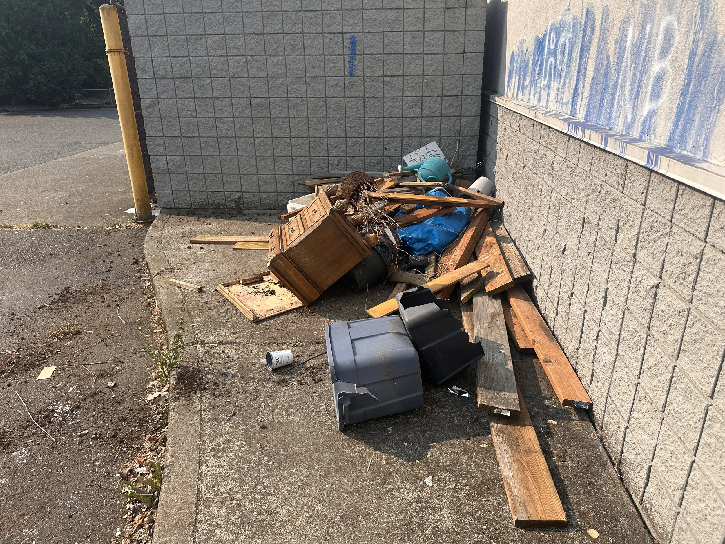 Discarded wooden dresser, lumber, and broken furniture at the former Rite Aid commercial property in Puyallup, Washington.