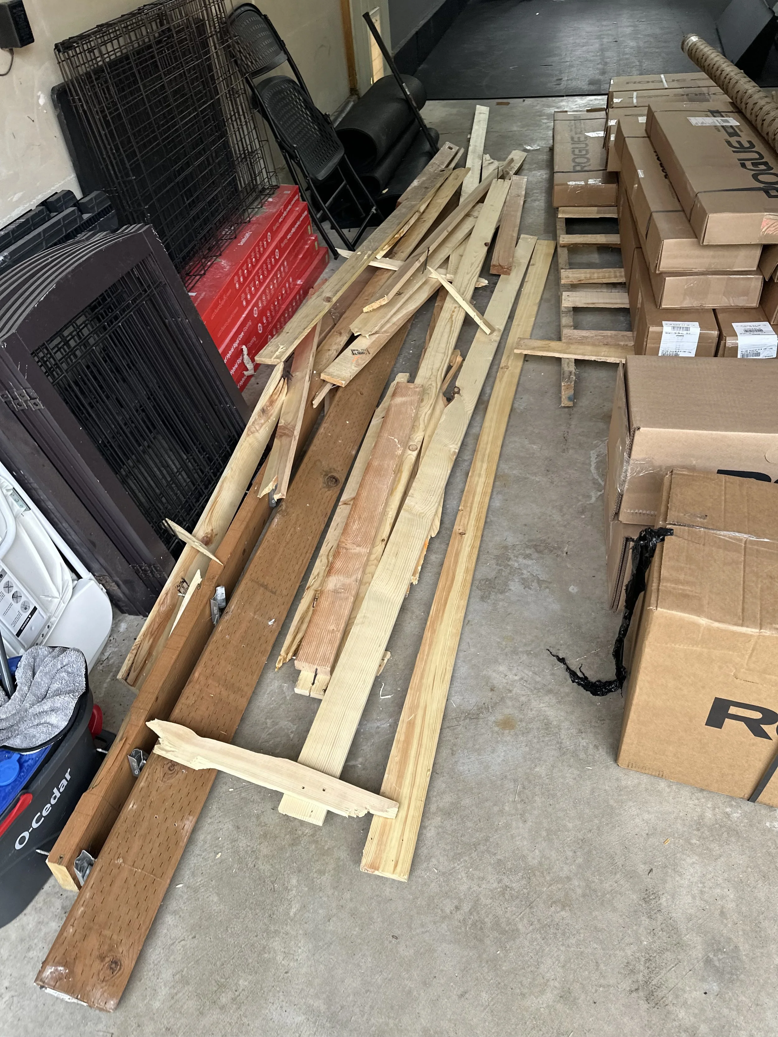 Large wooden shipping crates, cardboard packing tubes, pallets, and stored items inside a residential garage in Puyallup, WA.