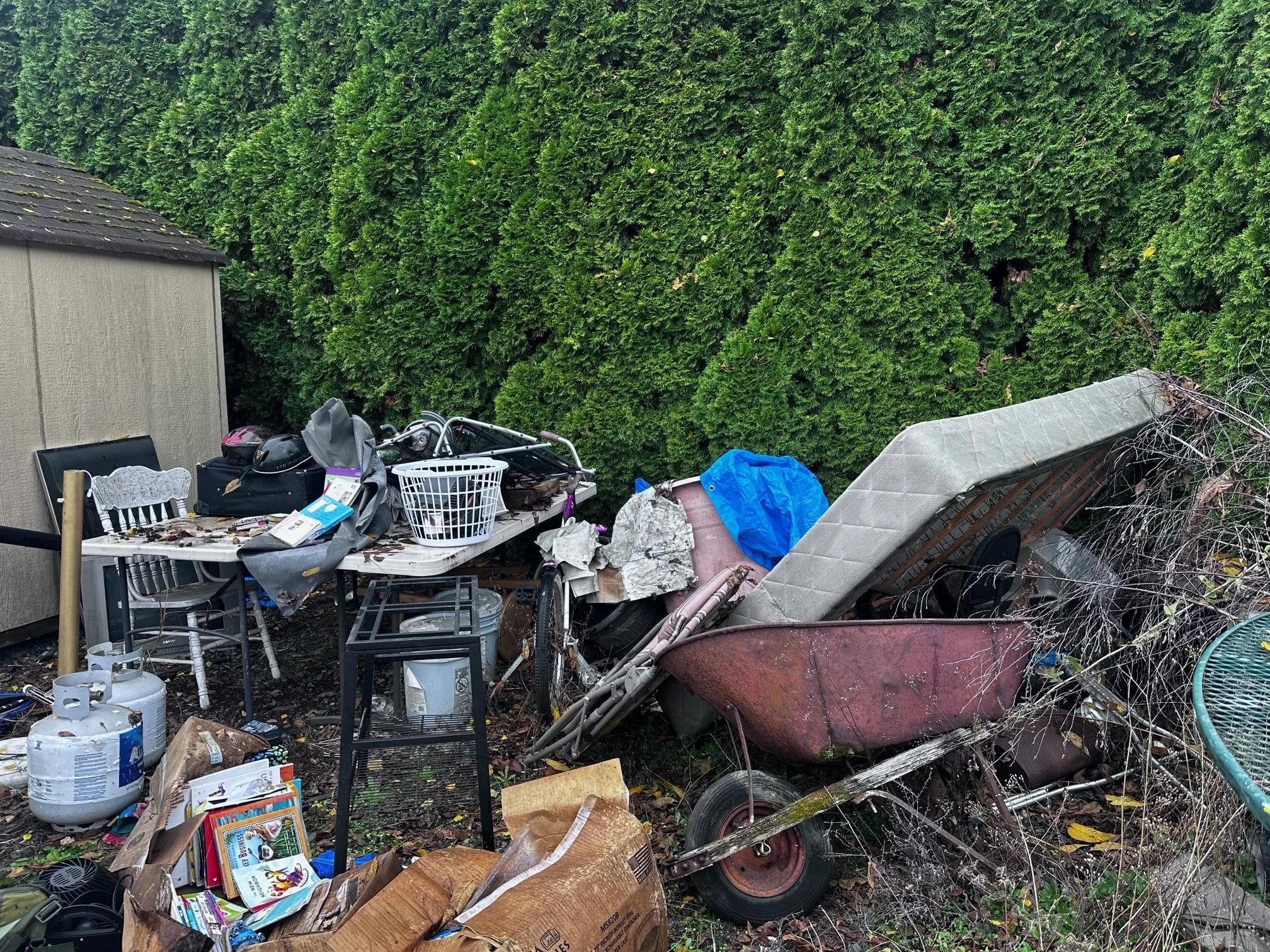 Before — old furniture, mattress, and yard junk stacked in the corner.