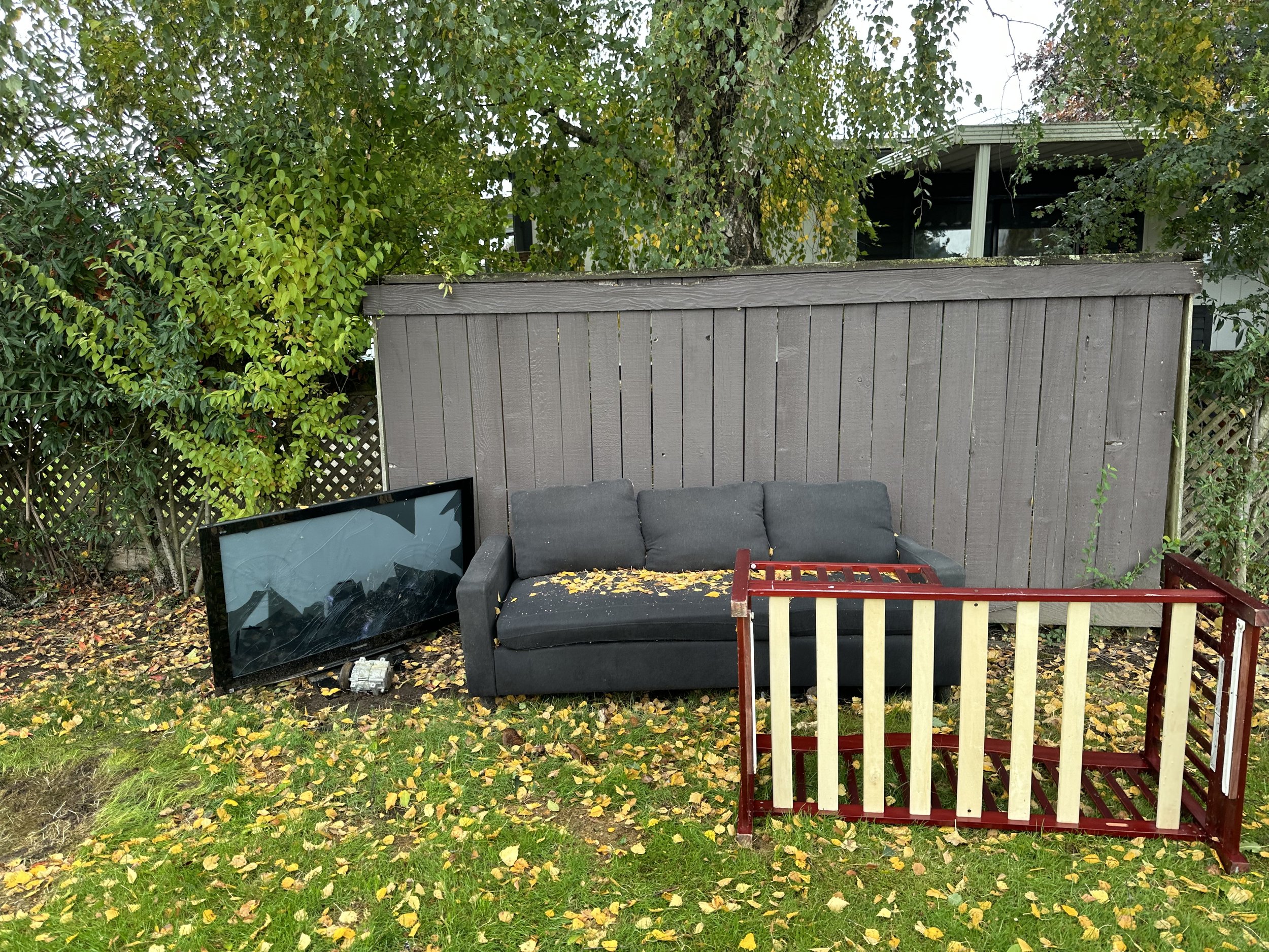 Before — couch, broken TV, and crib illegally dumped on the community grass.
