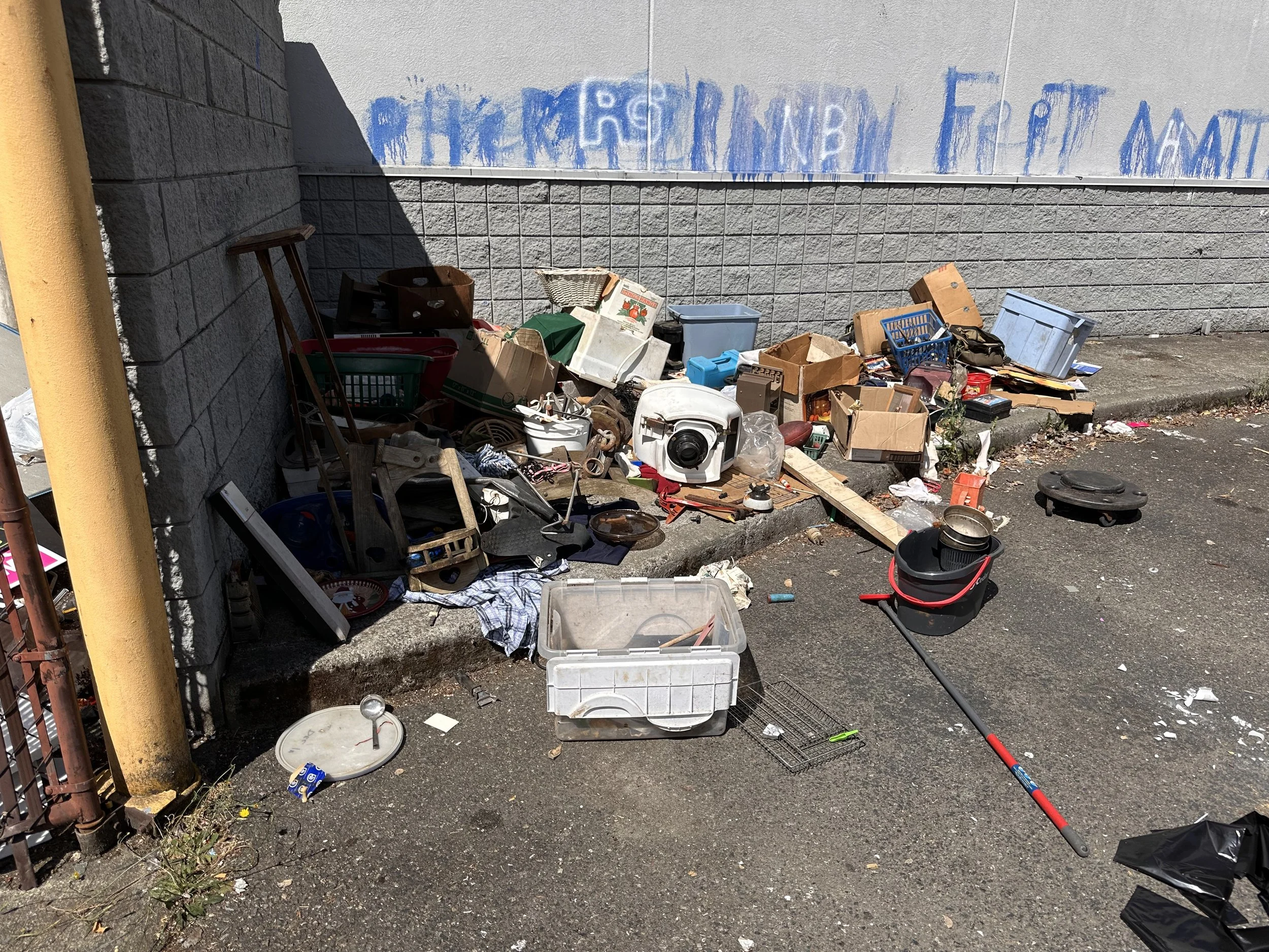 Illegally dumped household junk, boxes, and small appliances outside a commercial property in Puyallup, WA, serviced by Just Ask Alex.